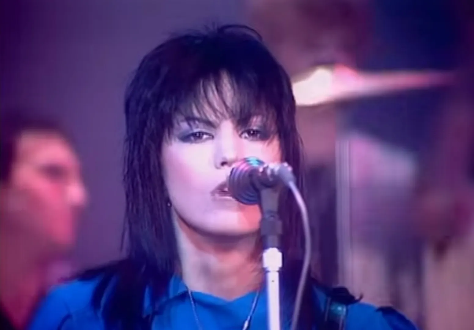 Female rock star from the 80s singing into a microphone on stage, embodying the spirit of 80s rock music.