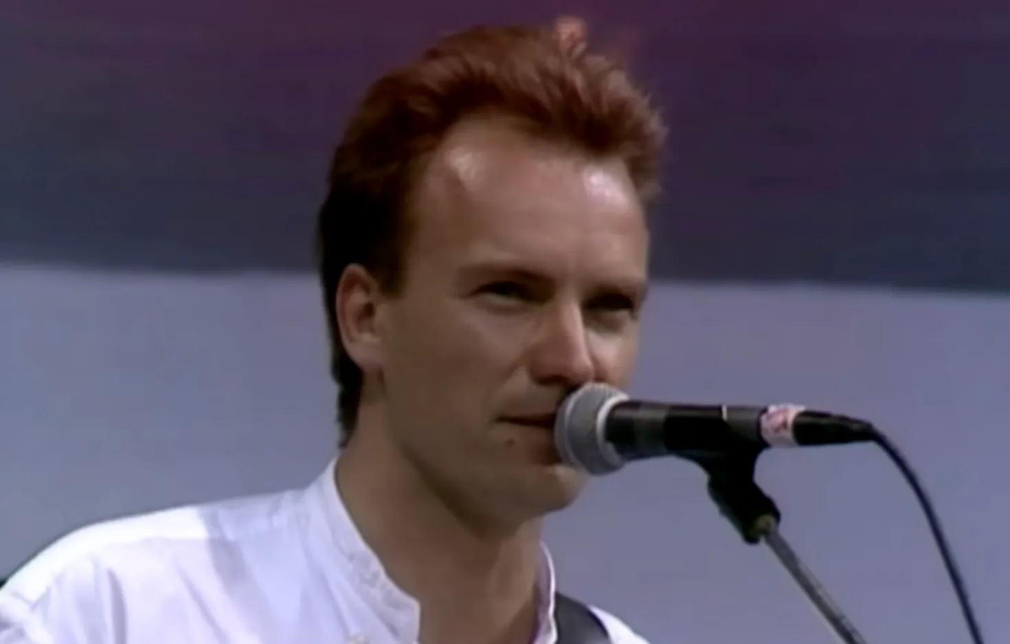 Lead singer of The Police performing on stage with a microphone, famous 80s musician and solo artist.