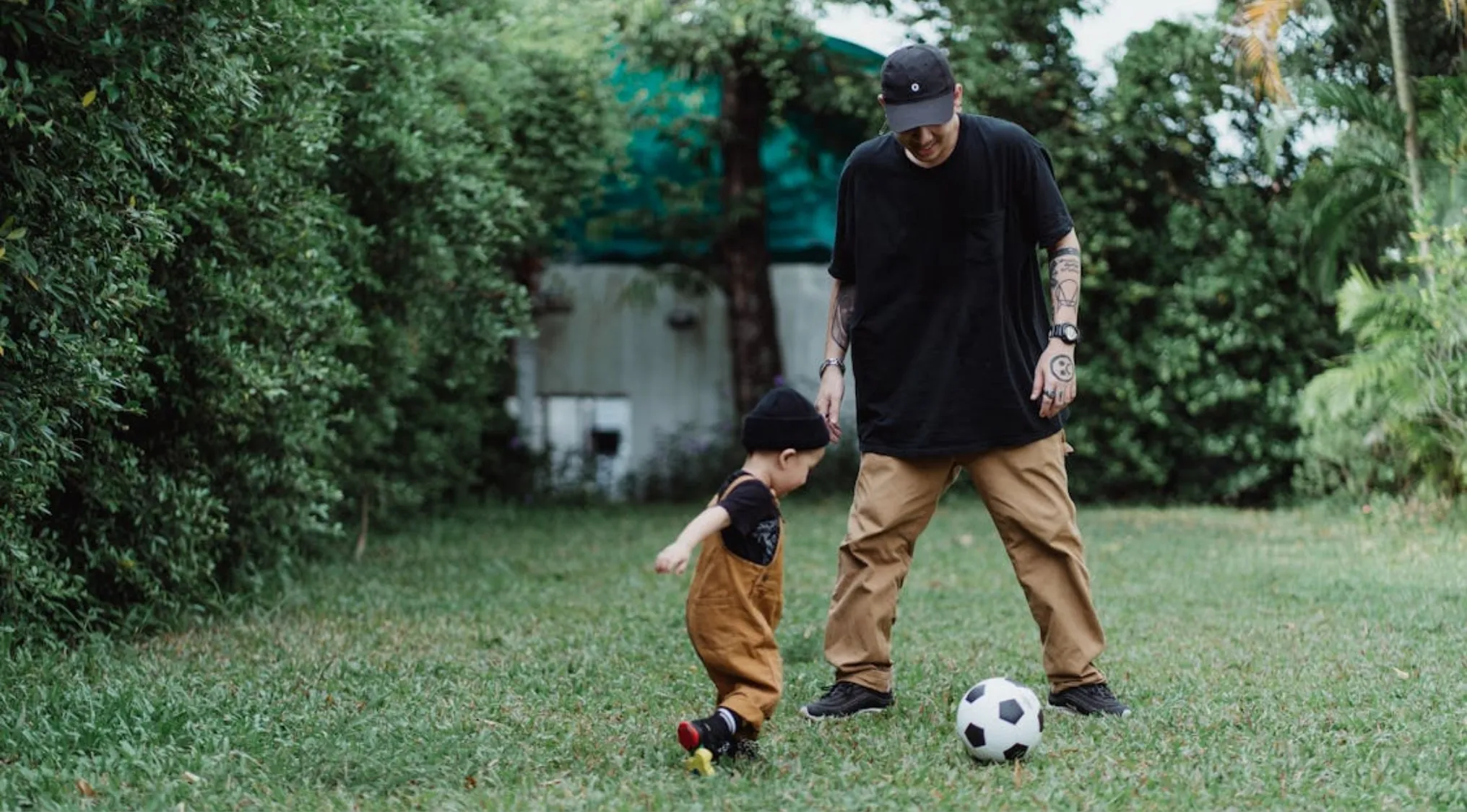 Adult and child playing soccer outside in a garden, illustrating the basic unit of heredity passed from parents to offspring.
