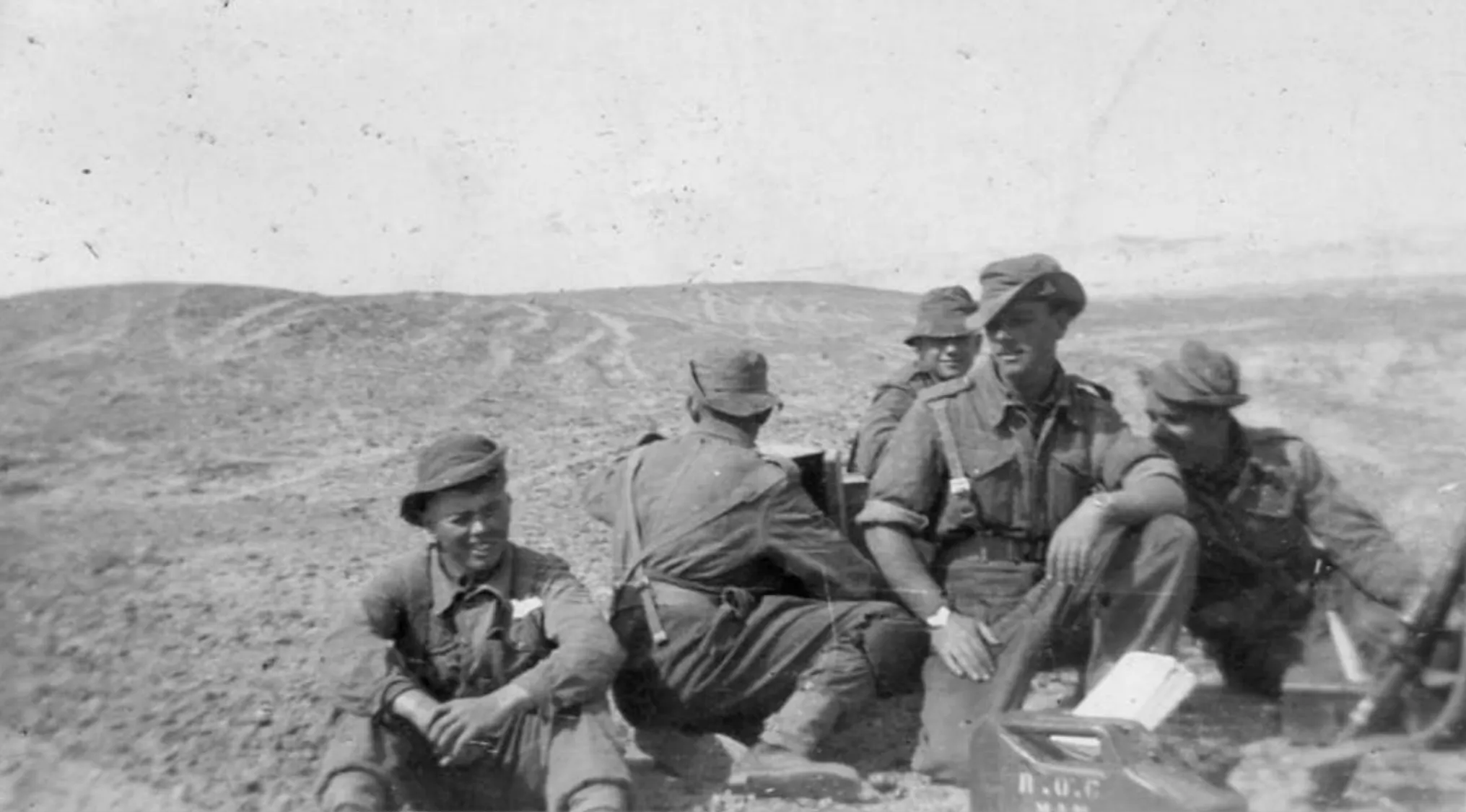 Group of World War II soldiers resting in a barren landscape, illustrating the historical event marking the war's beginning in Europe.
