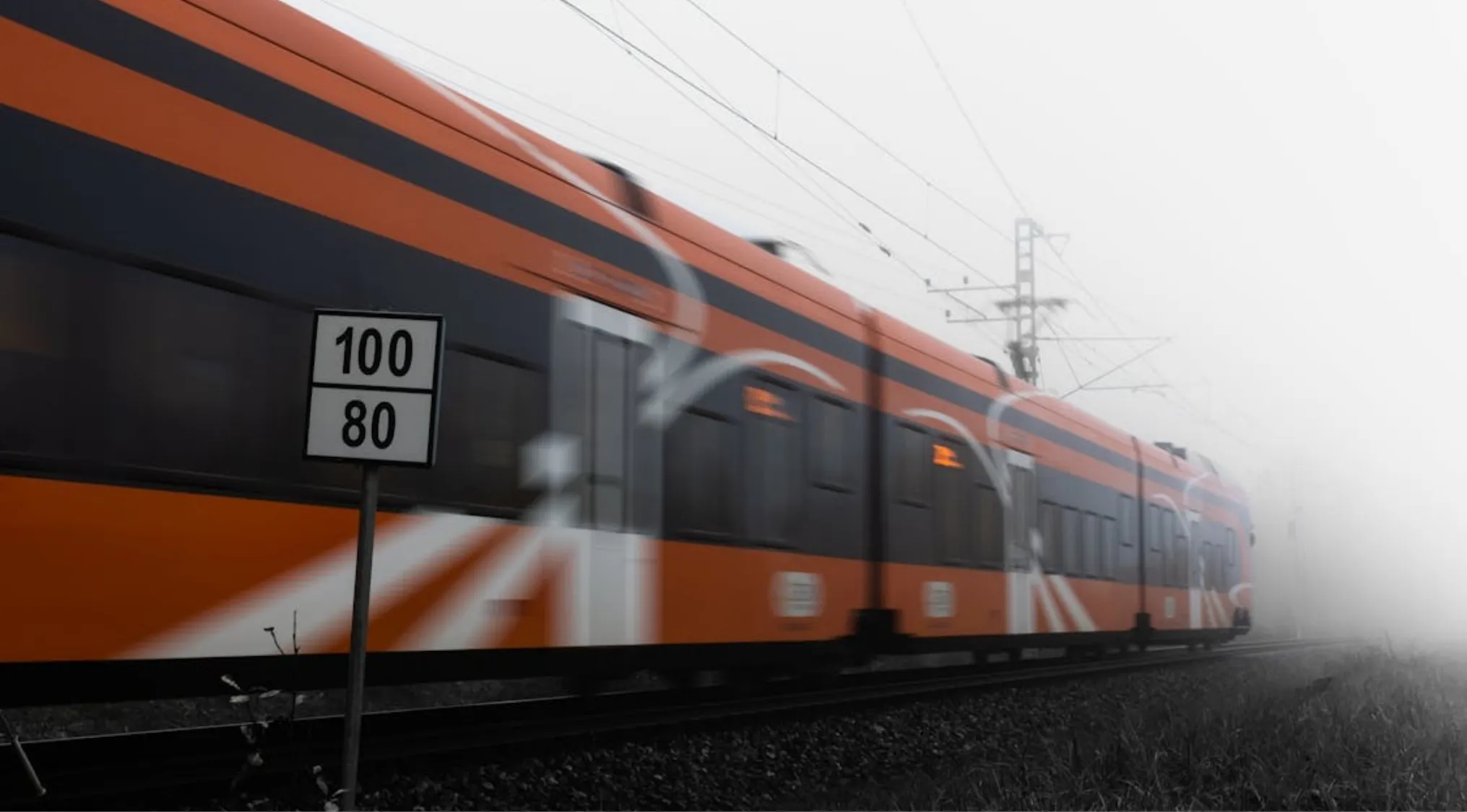 Orange and black train speeding along the tracks with motion blur, illustrating average speed in math school questions.