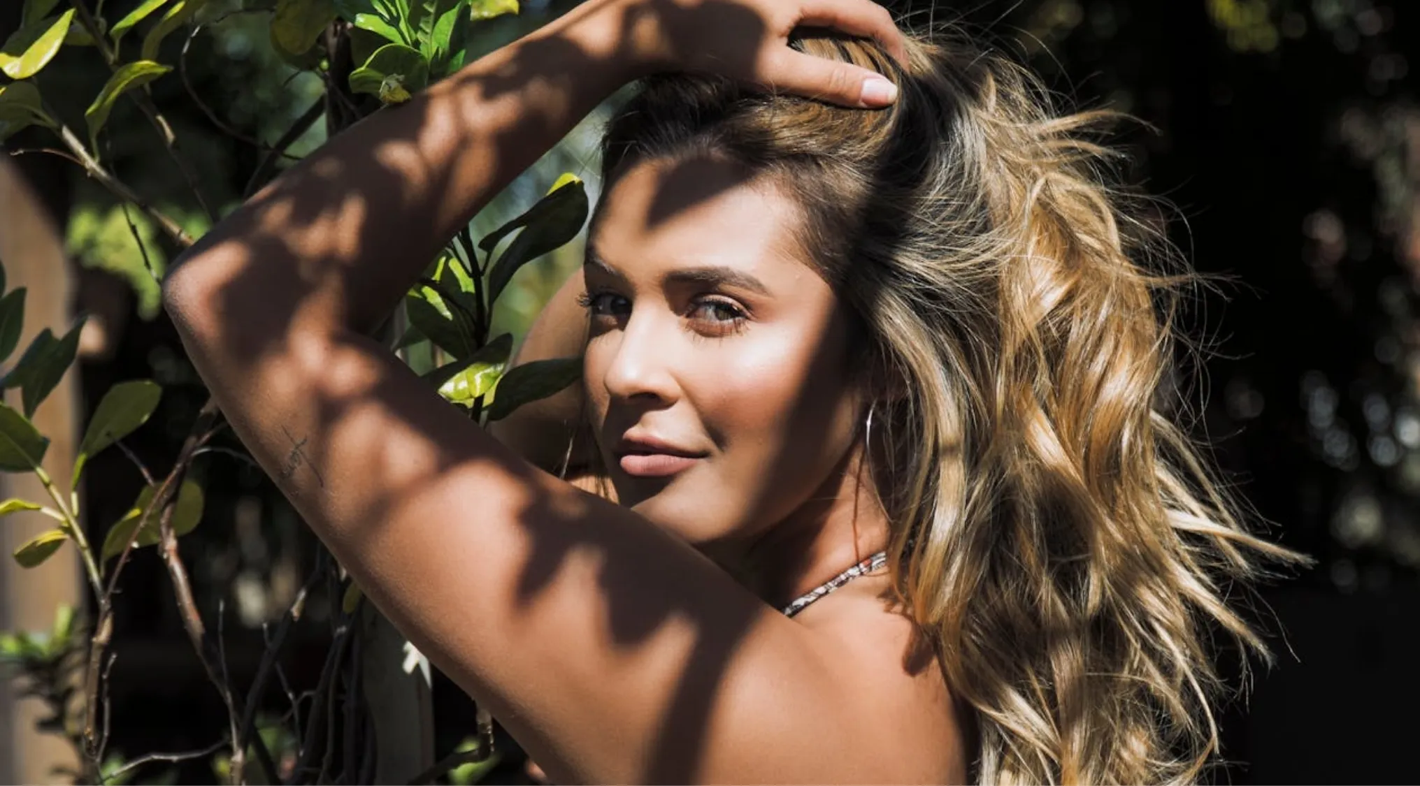 Young woman with flowing hair posing outdoors with shadows and light, illustrating human females and chromosomes concept.