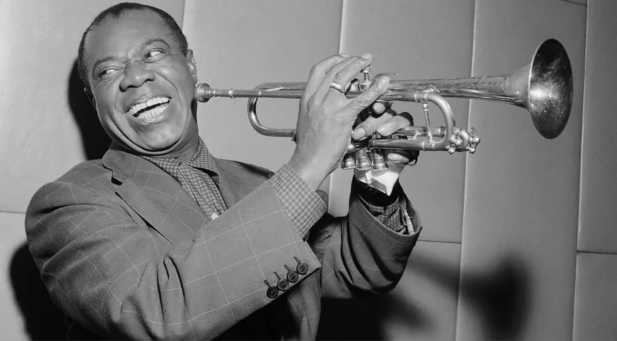 Famous jazz trumpeter smiling and holding trumpet in black and white portrait photo.