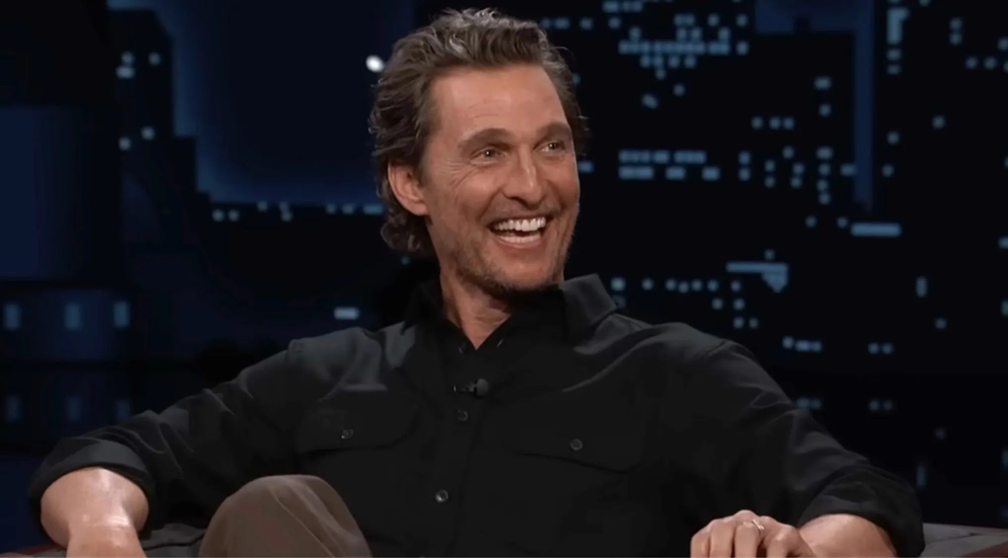 Matthew McConaughey smiling in a black shirt during a TV interview guessing the movie from a side character.
