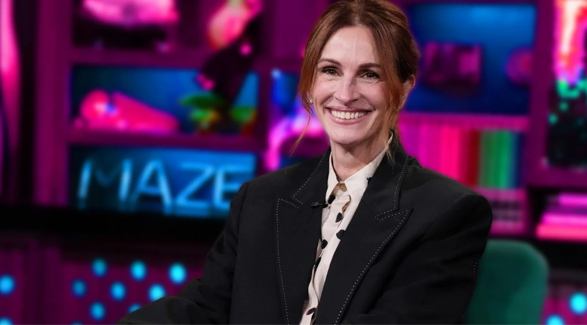 Julia Roberts smiling during an interview, dressed in a black blazer and patterned shirt, related to side character movies.