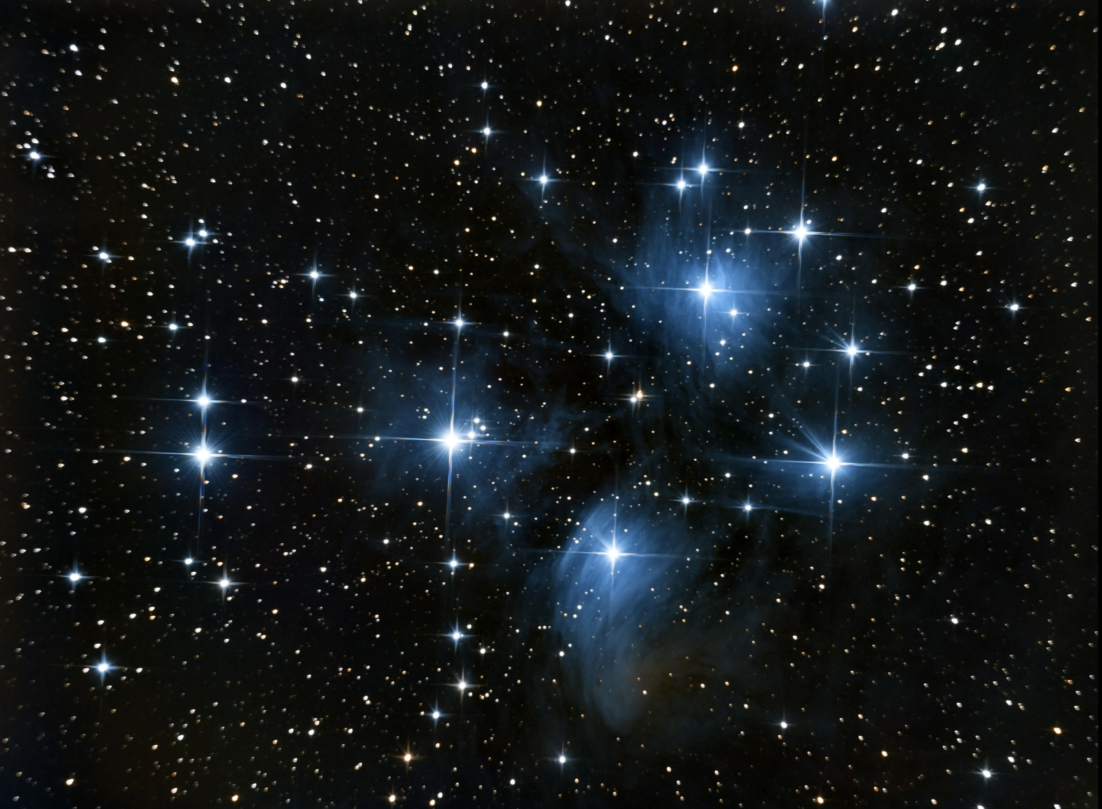 Bright blue stars in a star cluster with surrounding dust, illustrating star color indicating surface temperature in astronomy.