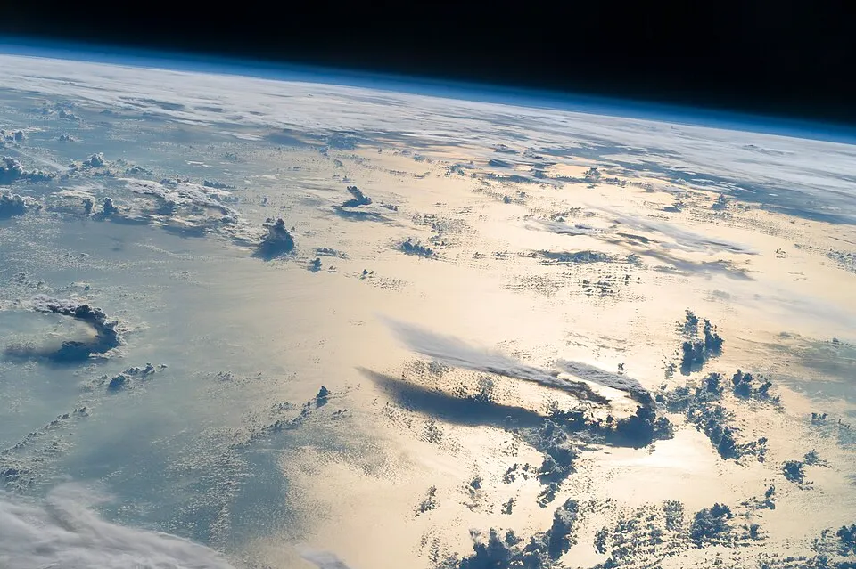 View of Earth's surface from space showing sunlight reflection illustrating reflectivity affecting climate conditions.