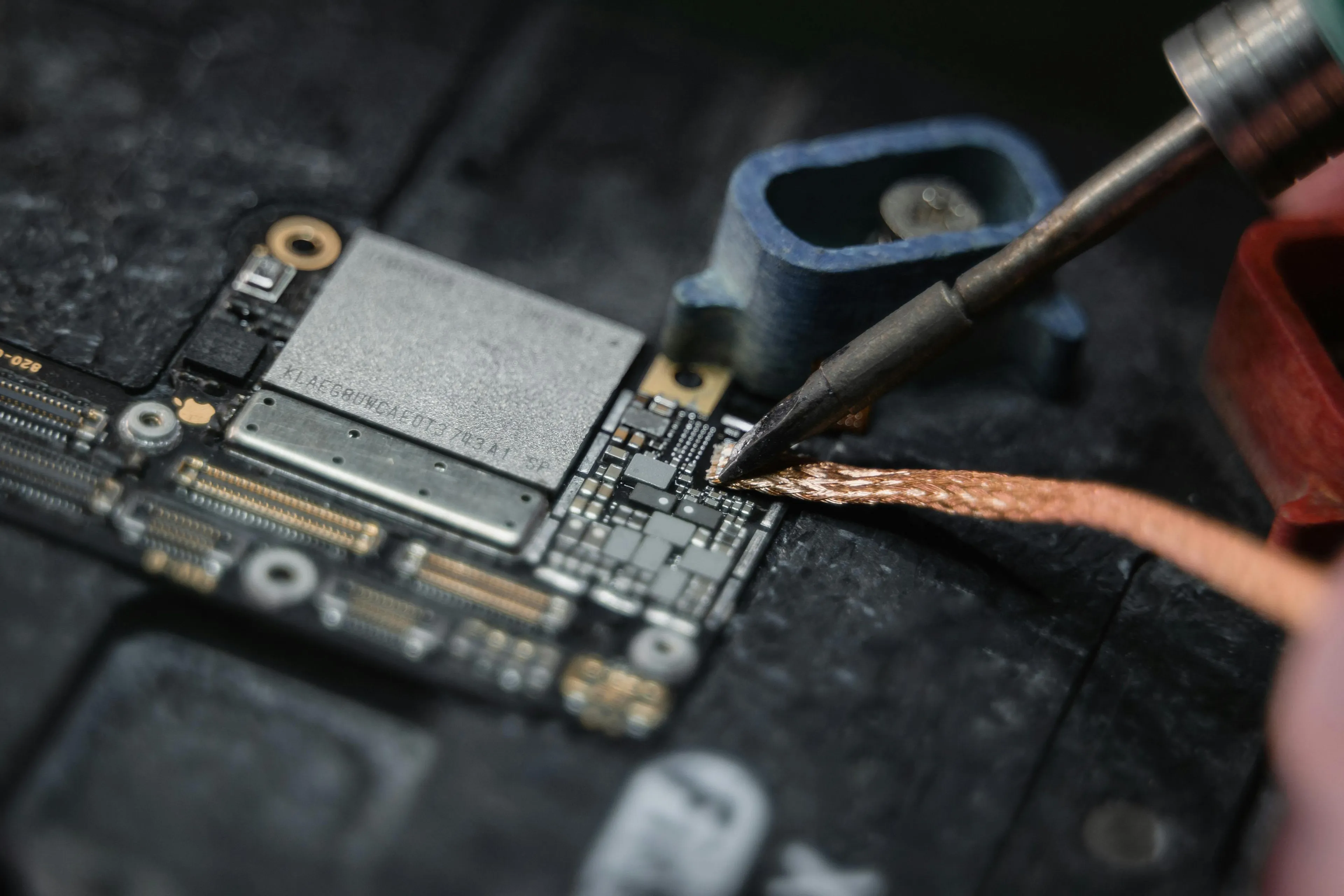 Close-up of an engineer soldering a thin wire on a circuit board illustrating wire resistance in science general knowledge.