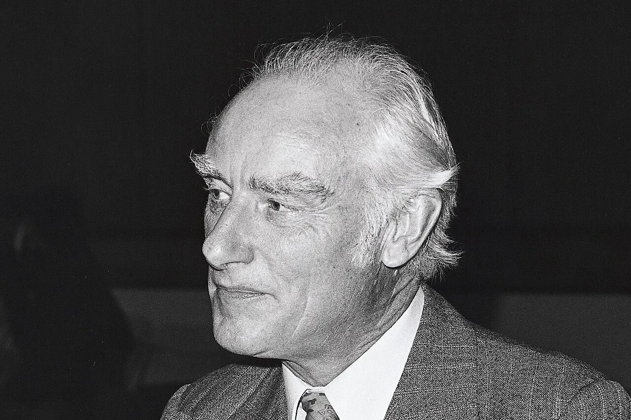 Older male scientist in a suit, known as father of genetics for discovering pea plant inheritance patterns.