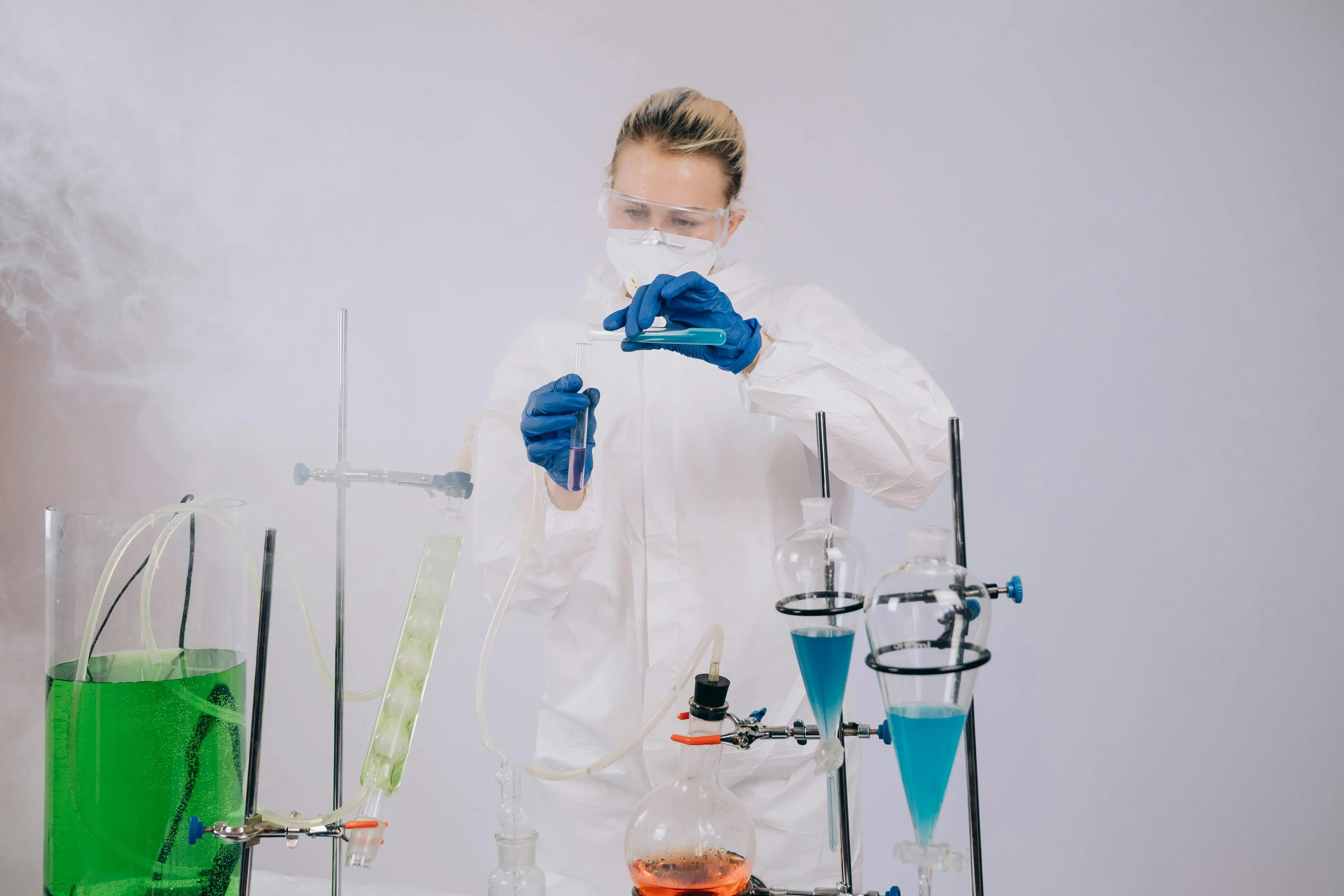 Lab student in protective gear conducting a science experiment mixing metal with acid releasing gas bubbles.