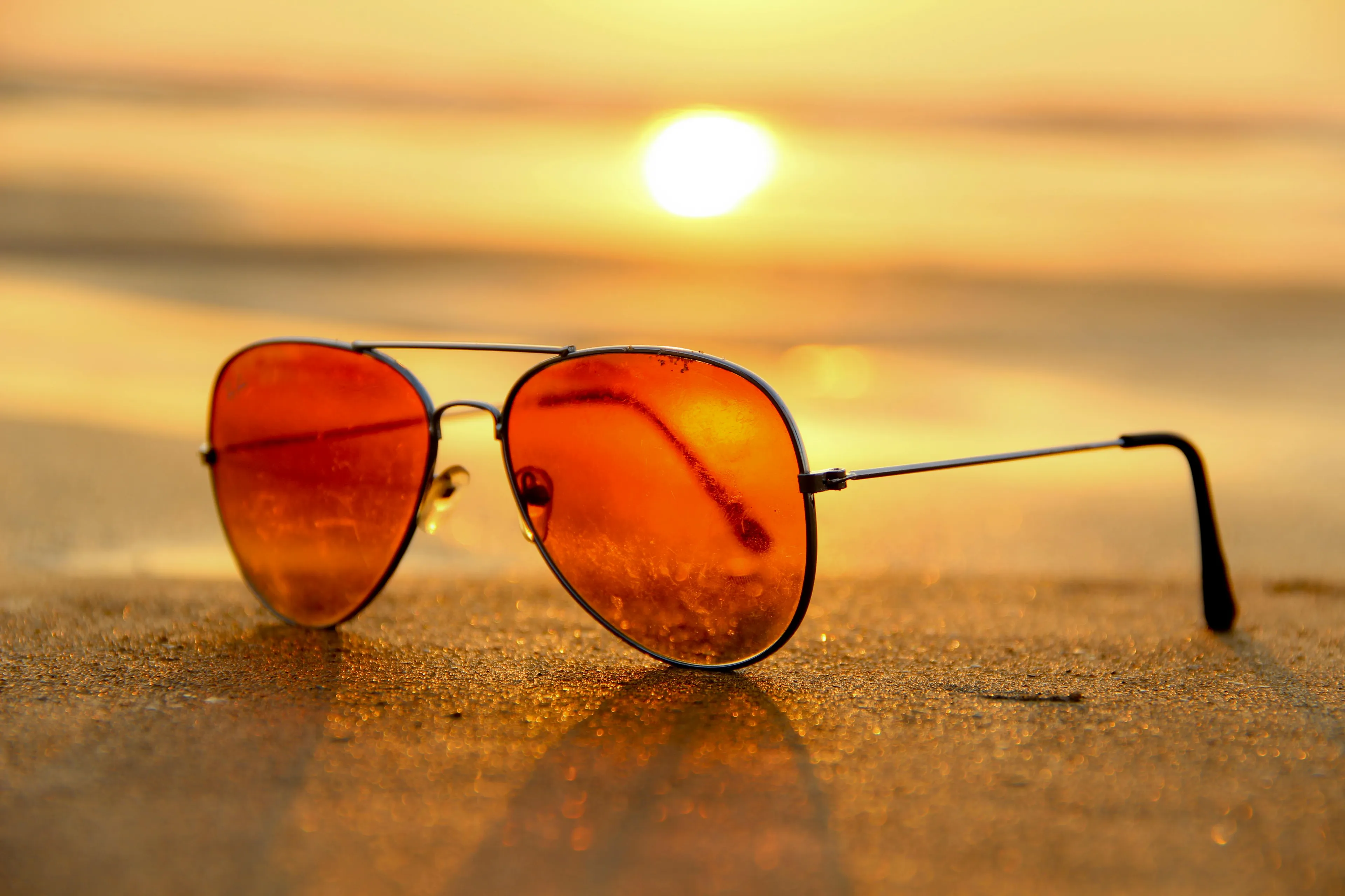 Sunglasses on sandy beach at sunset, symbolizing the summer season in Who Wants To Be A Millionaire $600 question.