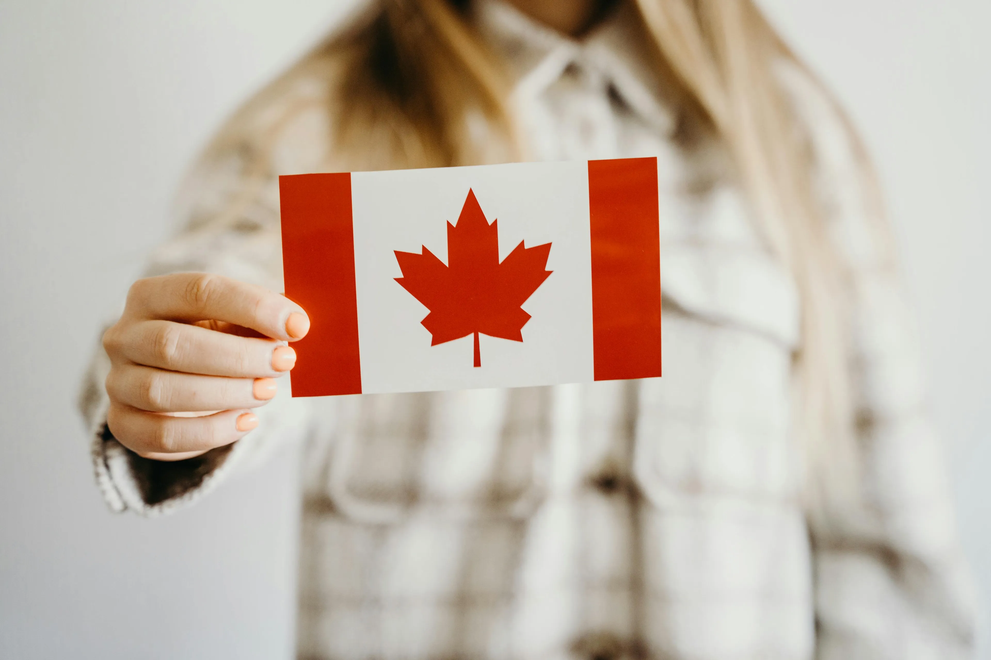 Person holding a Canadian flag card, related to Who Wants To Be A Millionaire Canada capital $2,000 question.