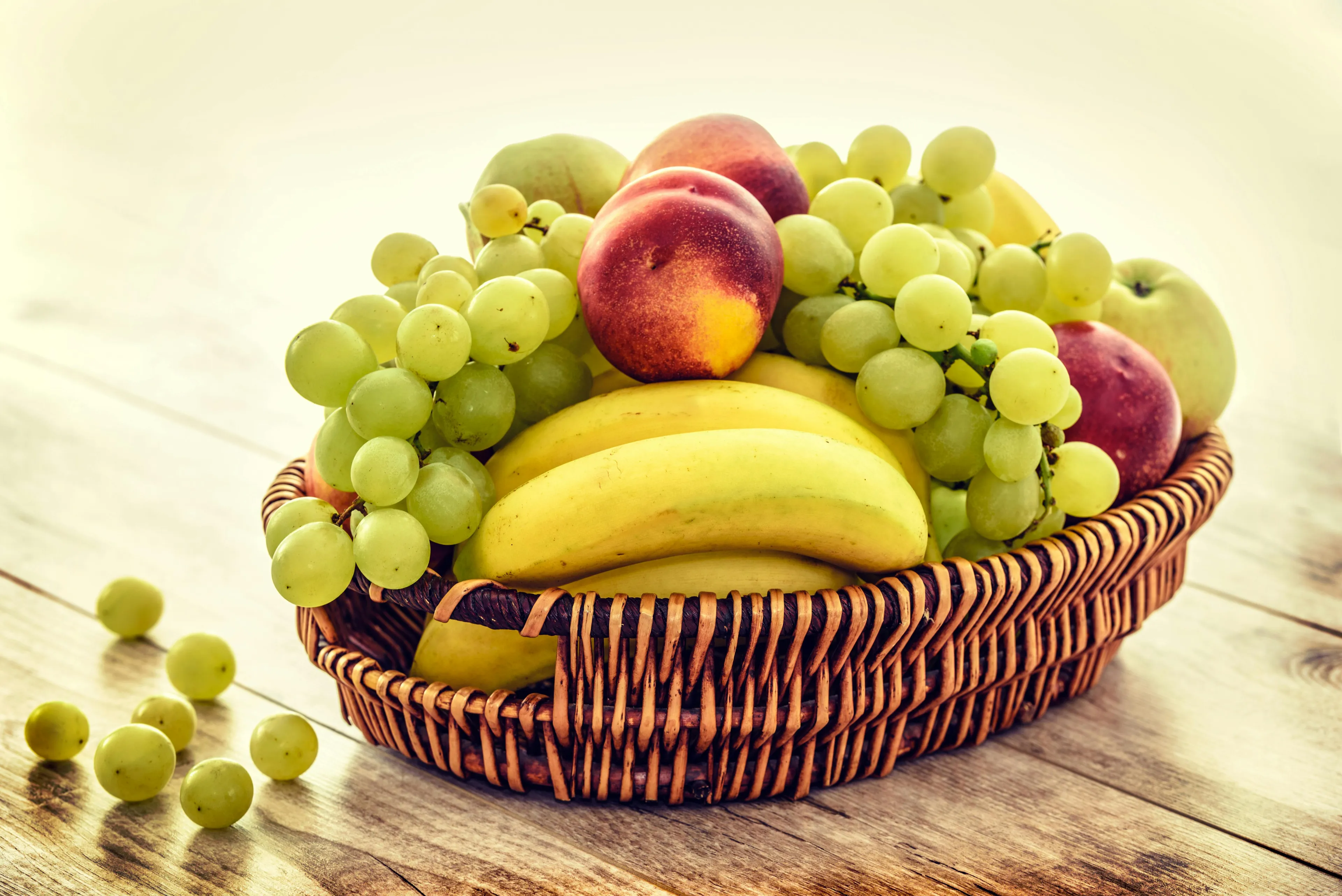 Basket of mixed fruit including bananas, grapes, peaches, and apples related to Discovery fruit variety question.