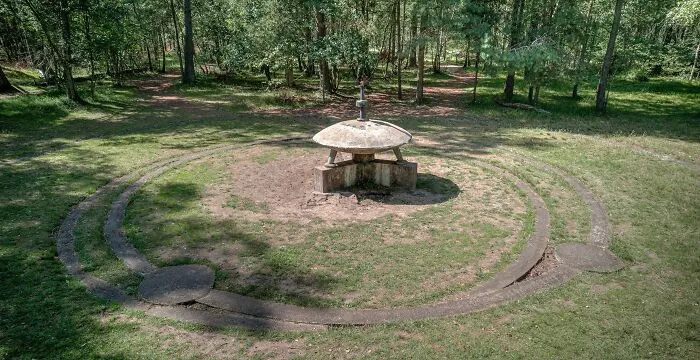 Unique circular stone monument in a grassy forest clearing among unusual places around the world with Wikipedia pages