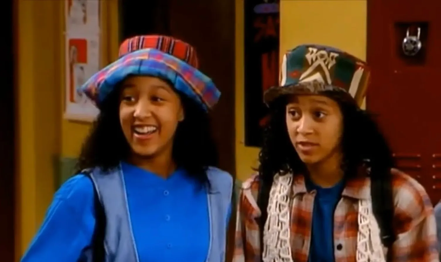 Twins from Sister Sister wearing colorful hats and casual 90s clothing, discovering their connection at school lockers.