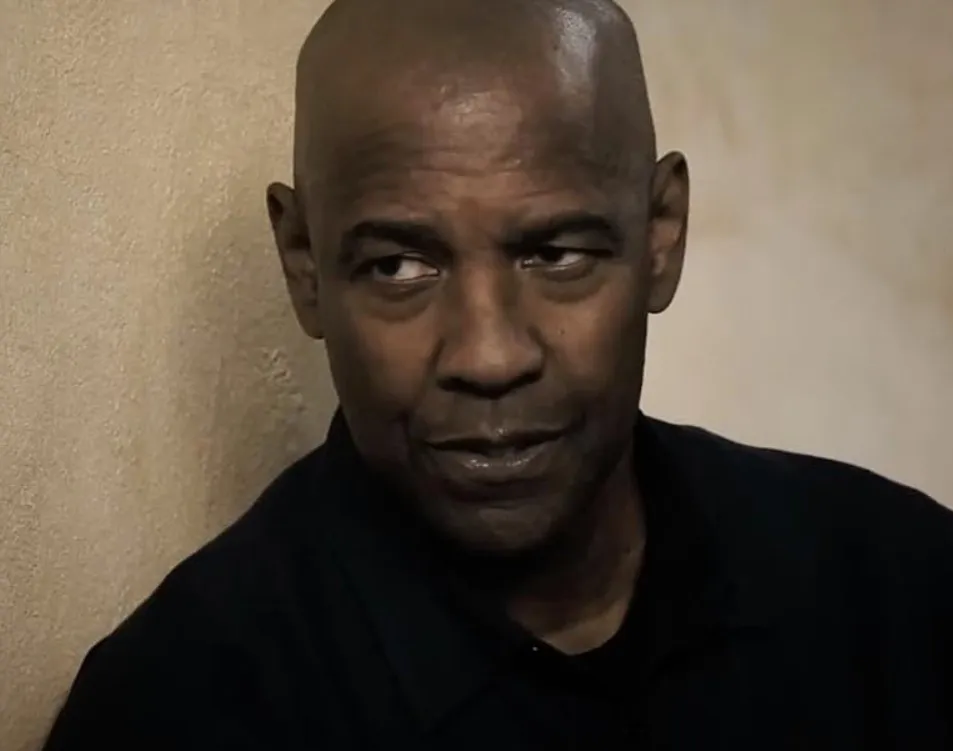 Close-up of a man looking sideways wearing a dark shirt, related to actors who used to be WWE wrestlers.