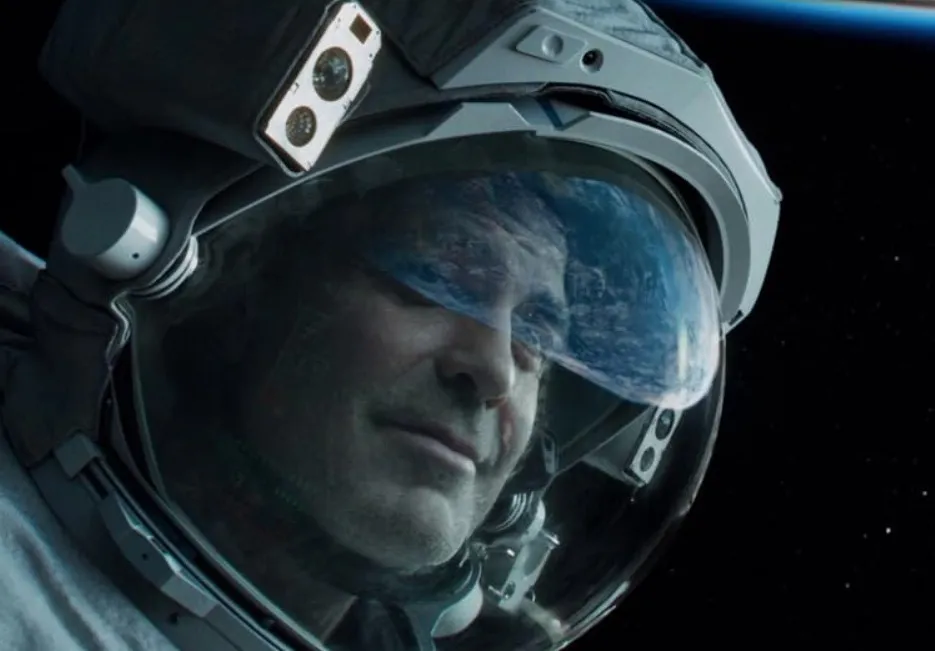 George Clooney in a spacesuit with Earth reflected in the visor, starring in the movie Gravity in outer space.