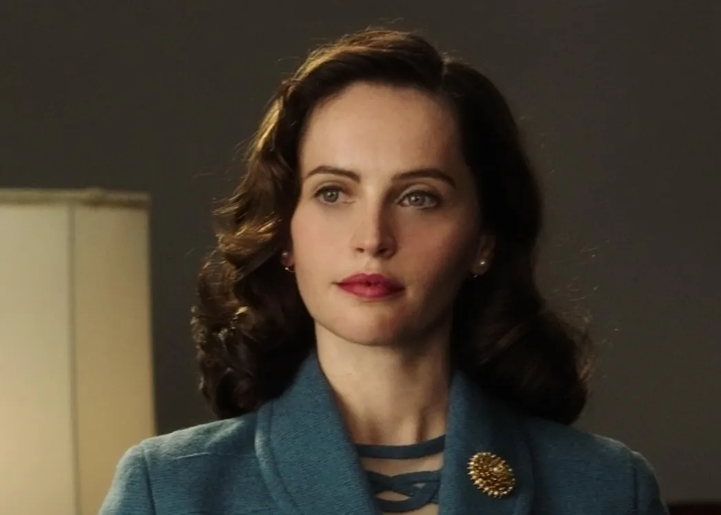 Felicity Jones in a blue outfit with vintage hairstyle, portraying a lead role in a film scene.