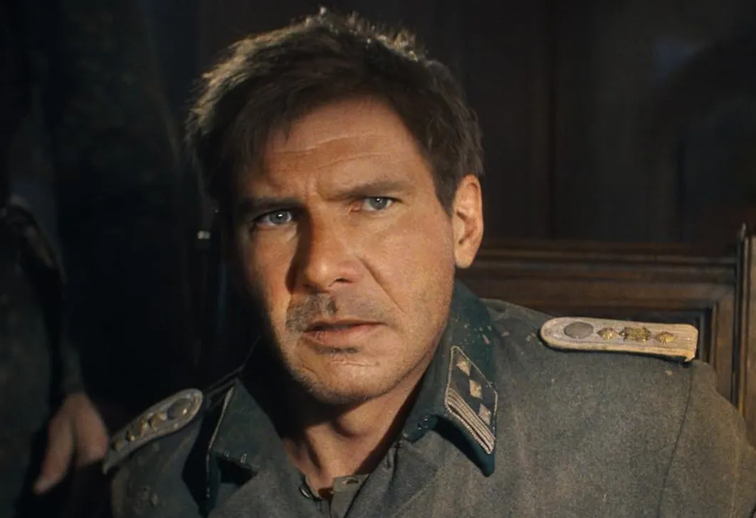 Harrison Ford in a military uniform, portraying a serious character in a dimly lit film scene.