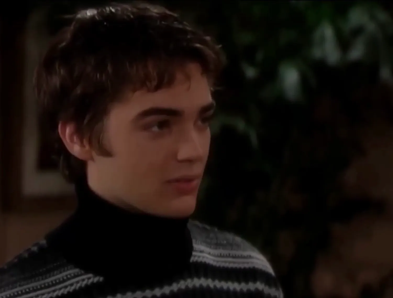 Young man wearing a black turtleneck and patterned sweater, representing Thomas Forrester head of Forrester Creations.