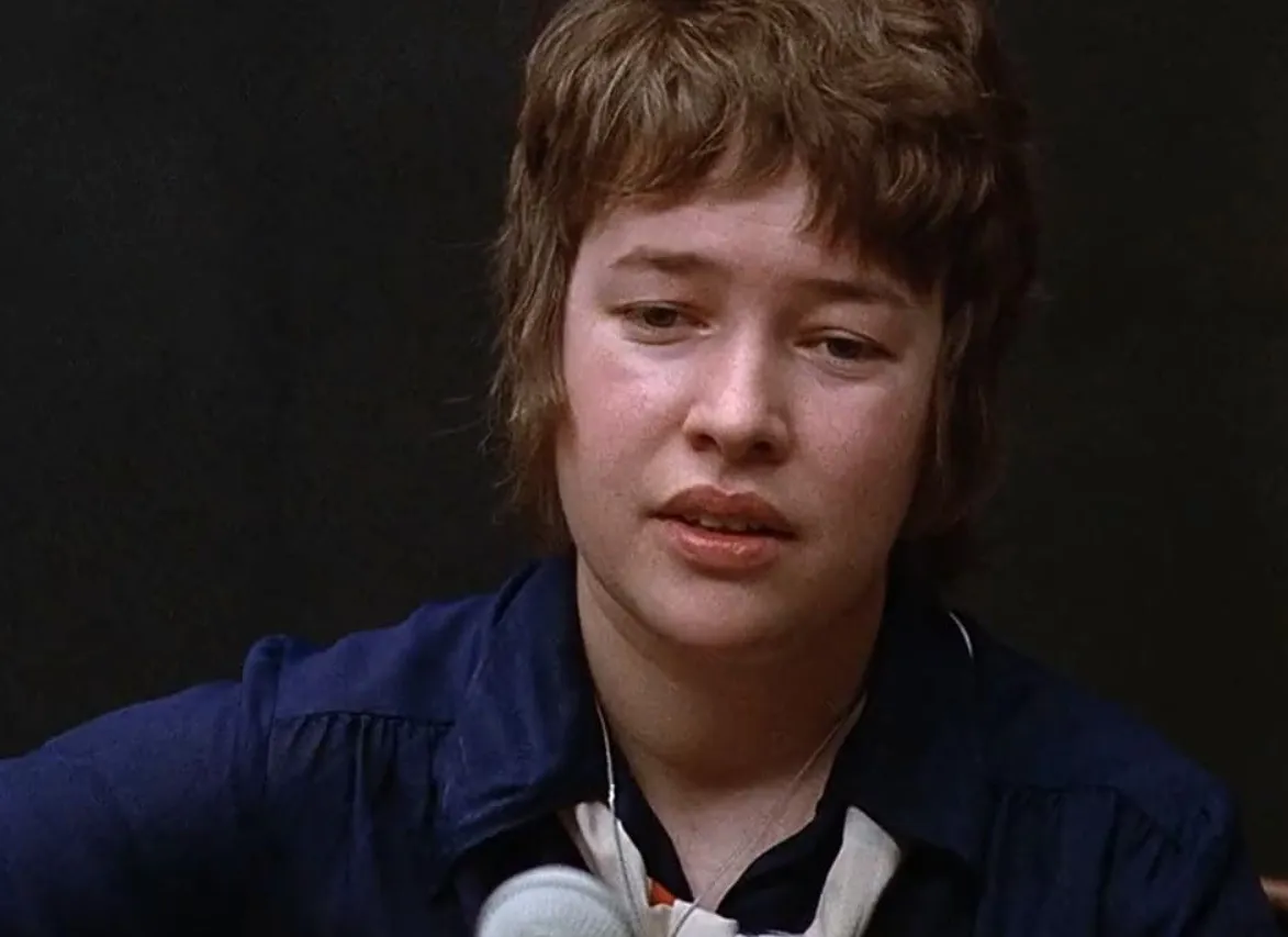 Young woman with short hair speaking into a microphone in a dark setting, related to actress Twilight film franchise.