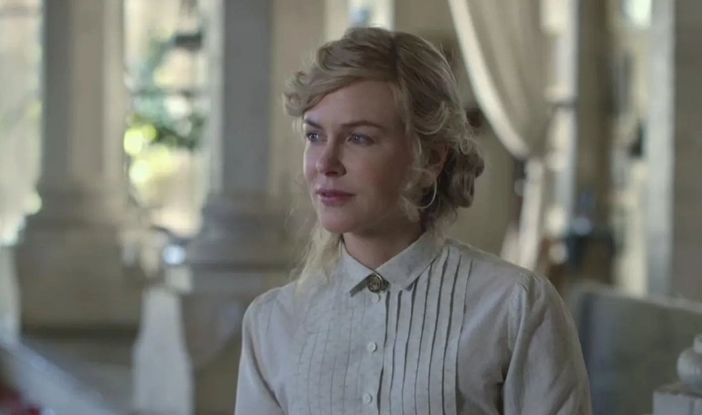Actress Nicole Kidman in a vintage blouse with curly blonde hair, standing in a softly lit classic interior.