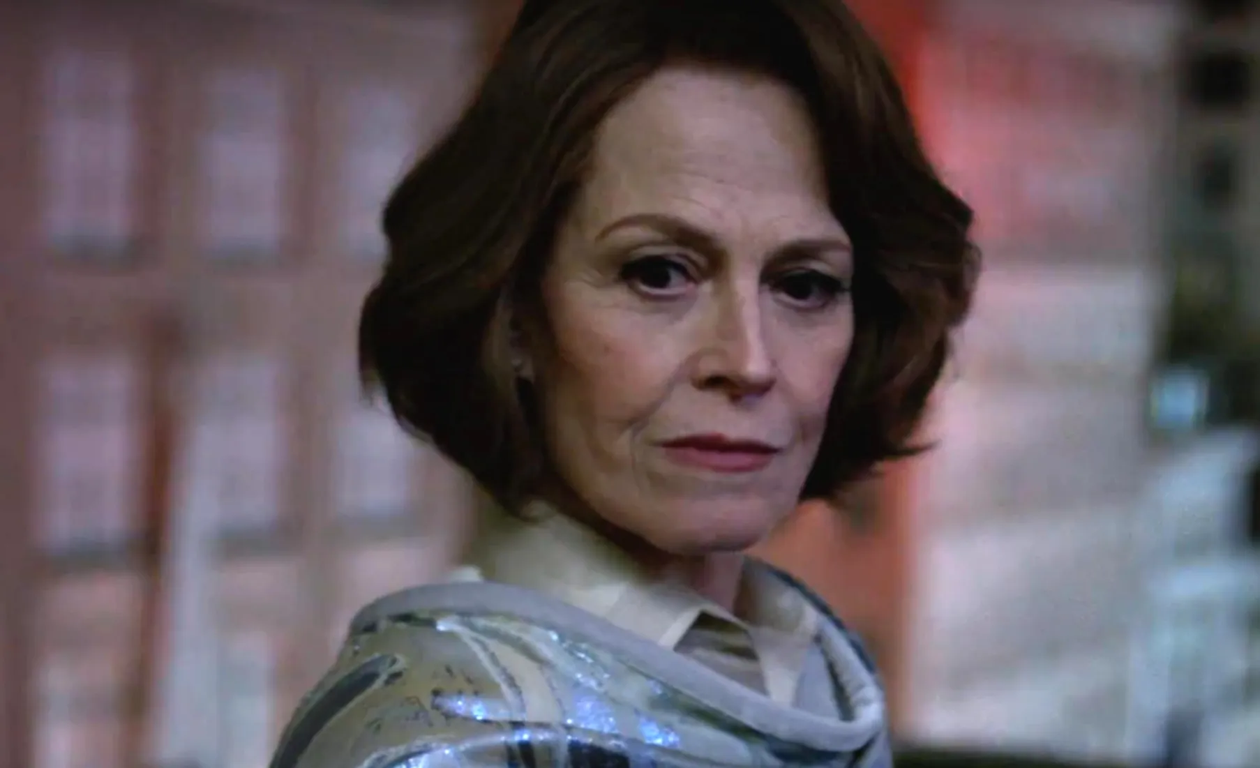 Famous actress with short brown hair wearing a shiny silver shawl in a softly lit indoor setting.