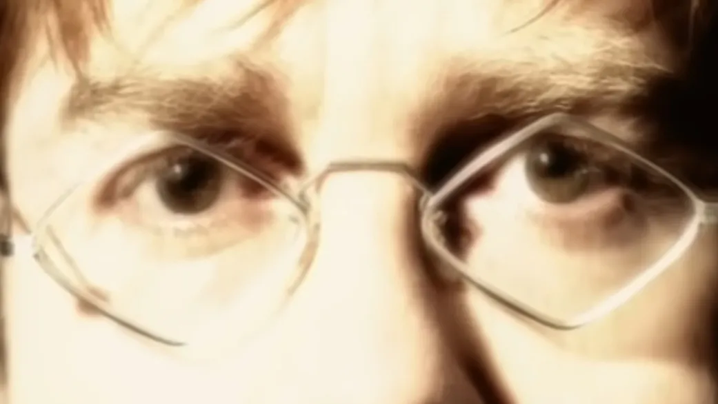 Close-up of a person’s eyes wearing thin silver glasses, focusing on celebrity eyes in a softly lit setting.