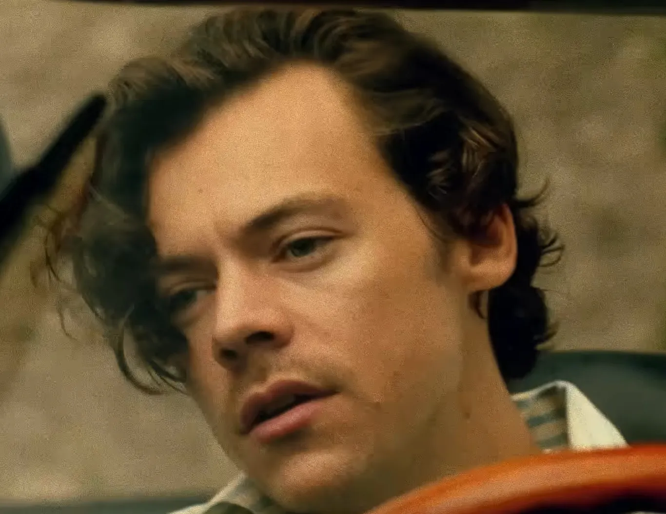 Close-up of Harry Styles with tousled hair, making eye contact in a casual setting.