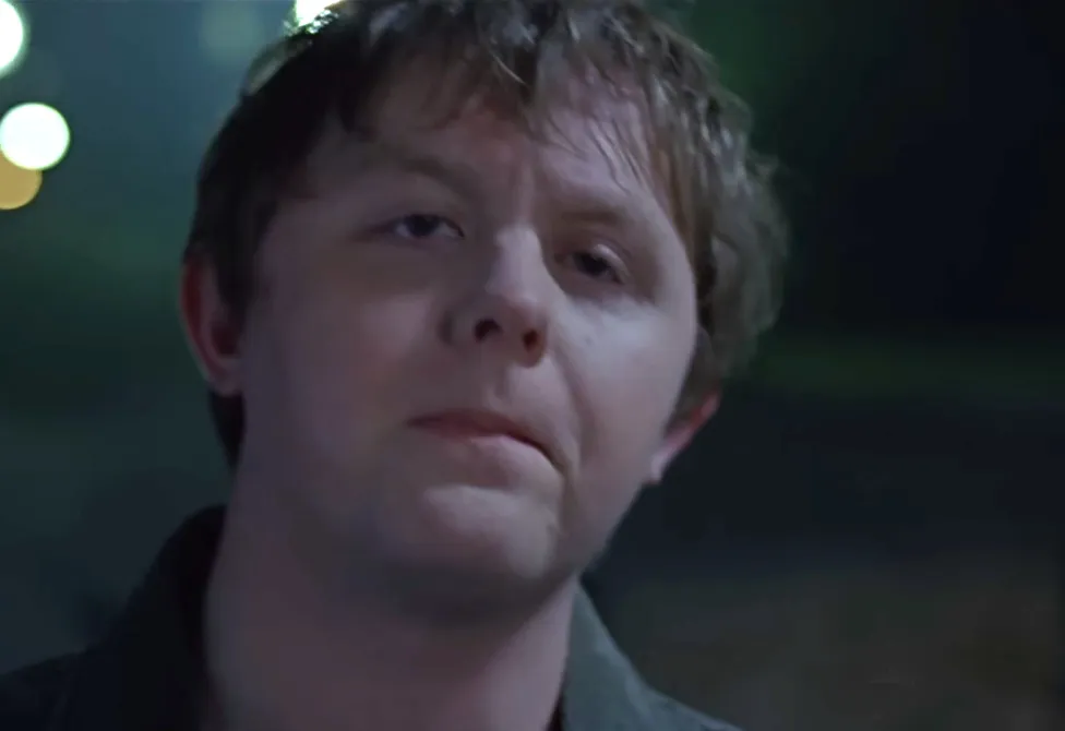 Close-up of Lewis Capaldi's eyes and face in a dimly lit outdoor setting at night.