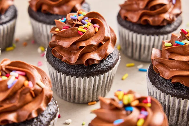 Chocolate decorated cupcakes with colorful sprinkles arranged on a table, perfect dessert to bring to a potluck.