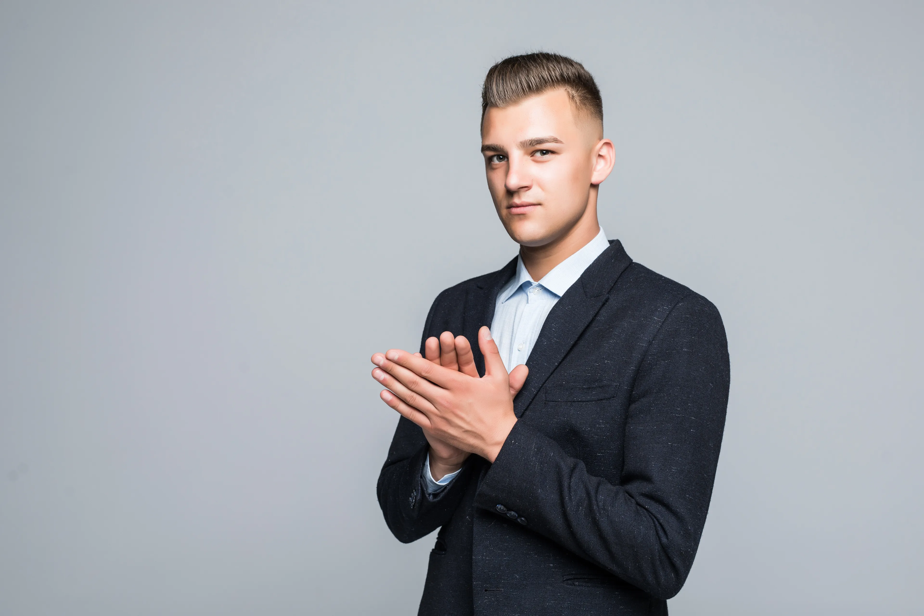 Young man in a suit clapping confidently, reflecting on where you fall on the narcissism scale and friend’s promotion reaction.