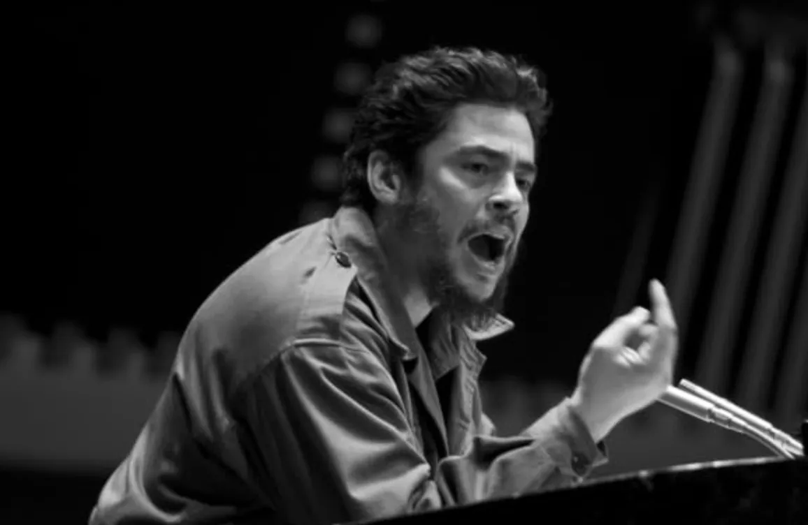 Benicio del Toro portraying a famous person in a 2008 movie scene, passionately speaking at a podium.