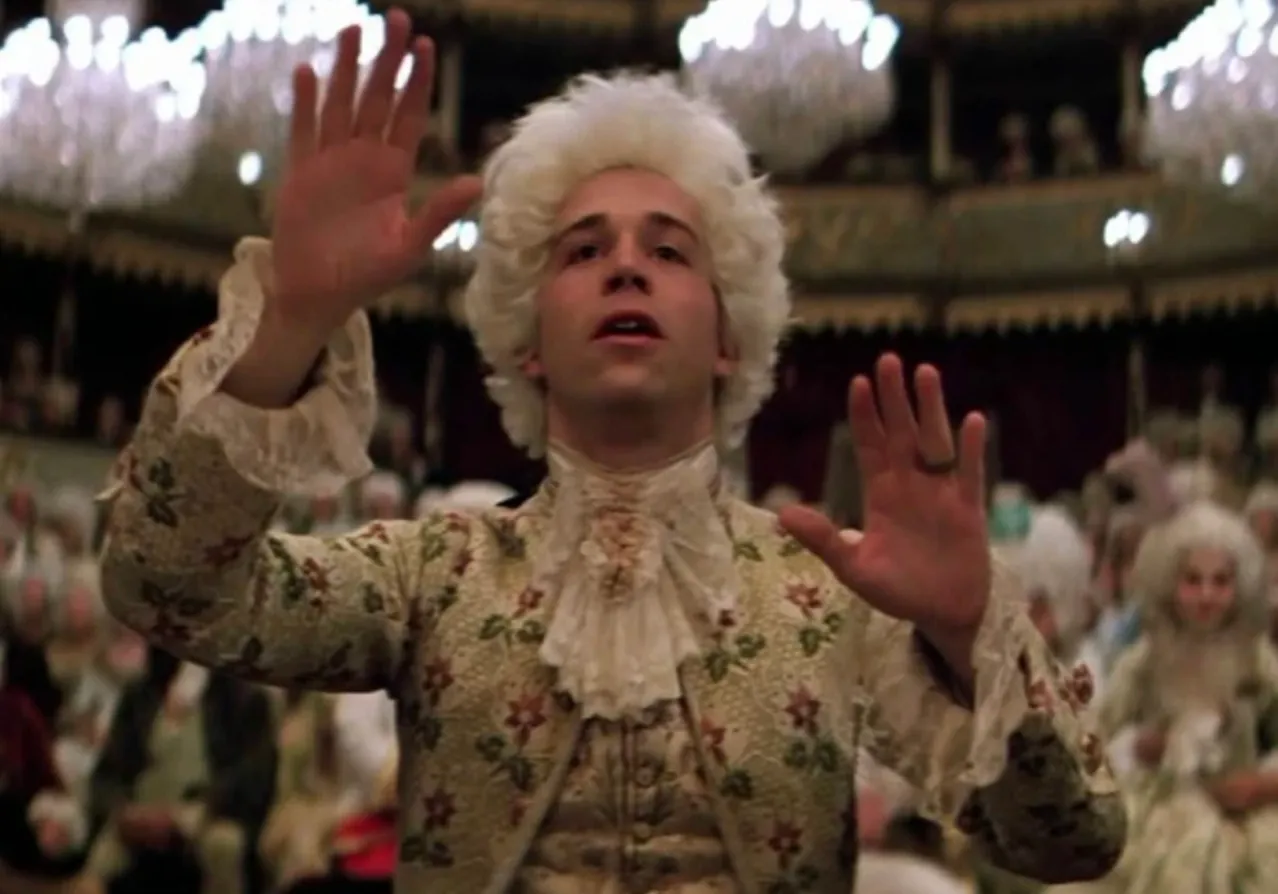 Actor dressed as composer Wolfgang Amadeus Mozart in a period costume conducting in a scene from Amadeus 1984 film.