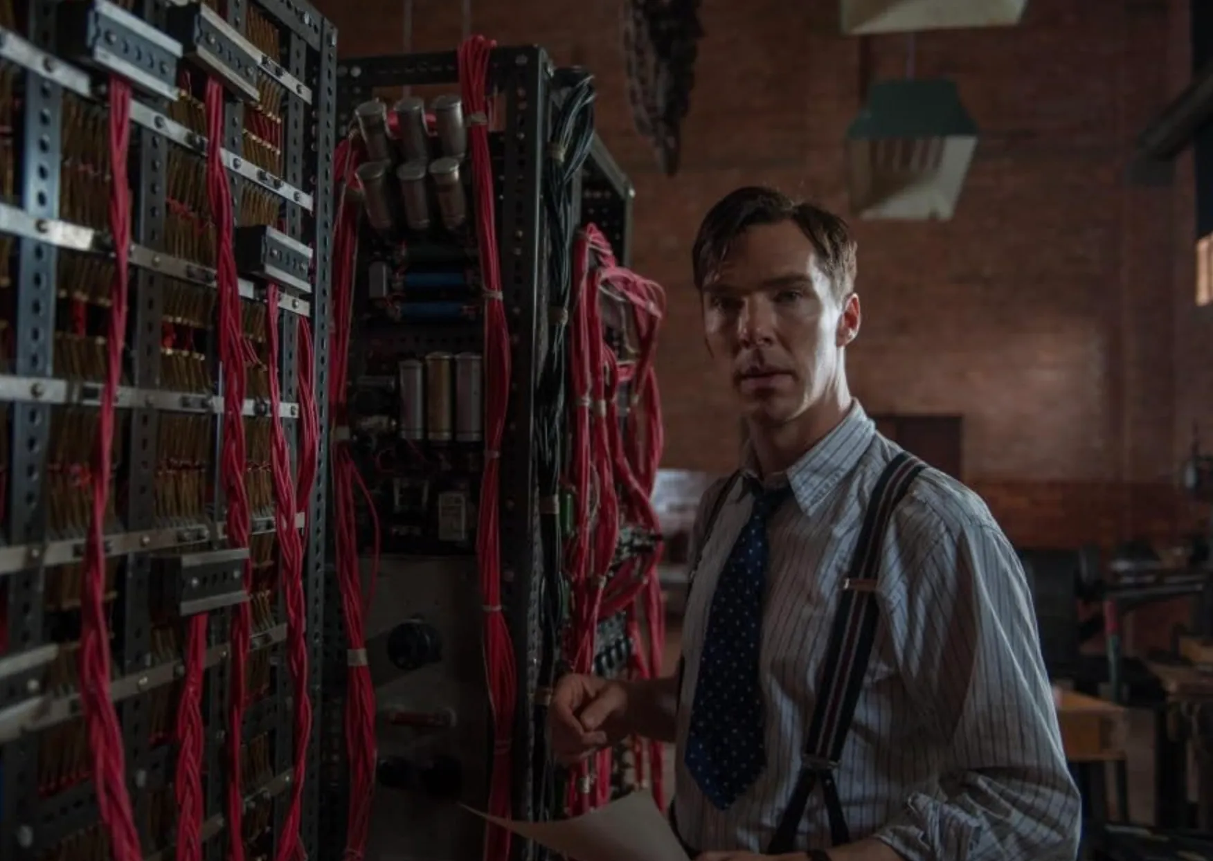 Benedict Cumberbatch in The Imitation Game portraying Alan Turing working on an early computing machine with wiring panels.