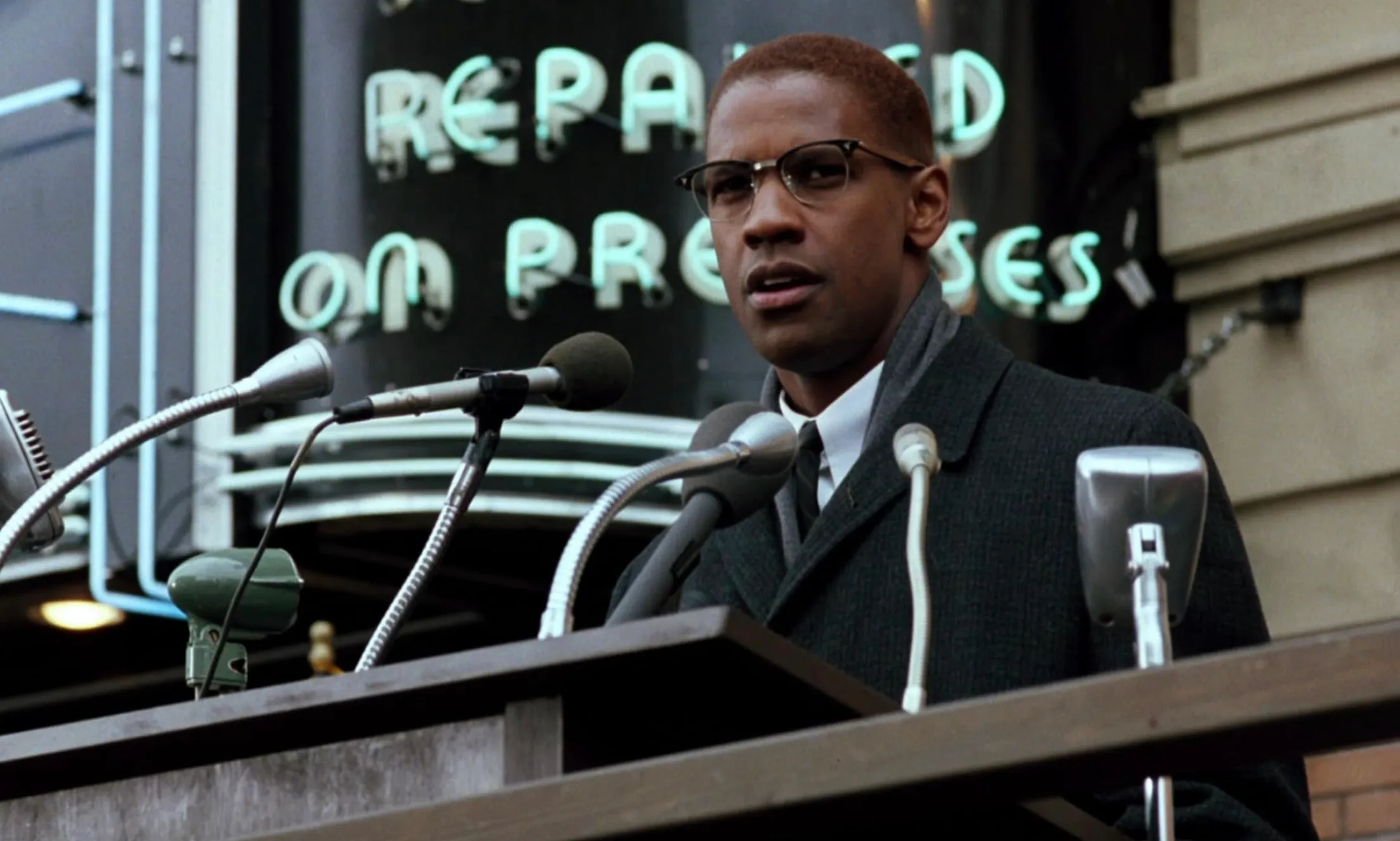 Denzel Washington portraying a character at a podium delivering a speech in a 1992 movie scene.