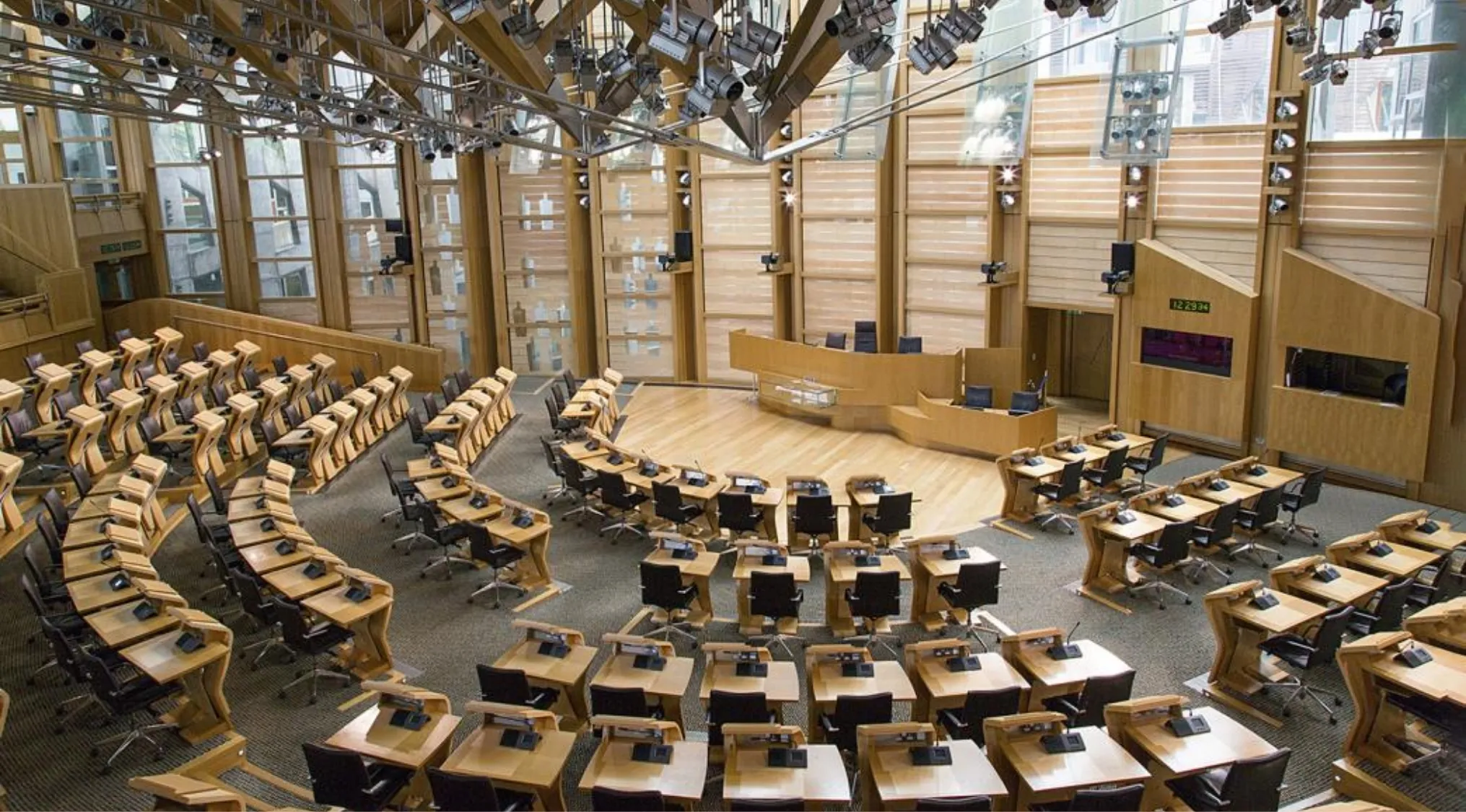 Empty Scottish Parliament debating chamber with wood desks and chairs illustrating areas Scottish Parliament can legislate on.