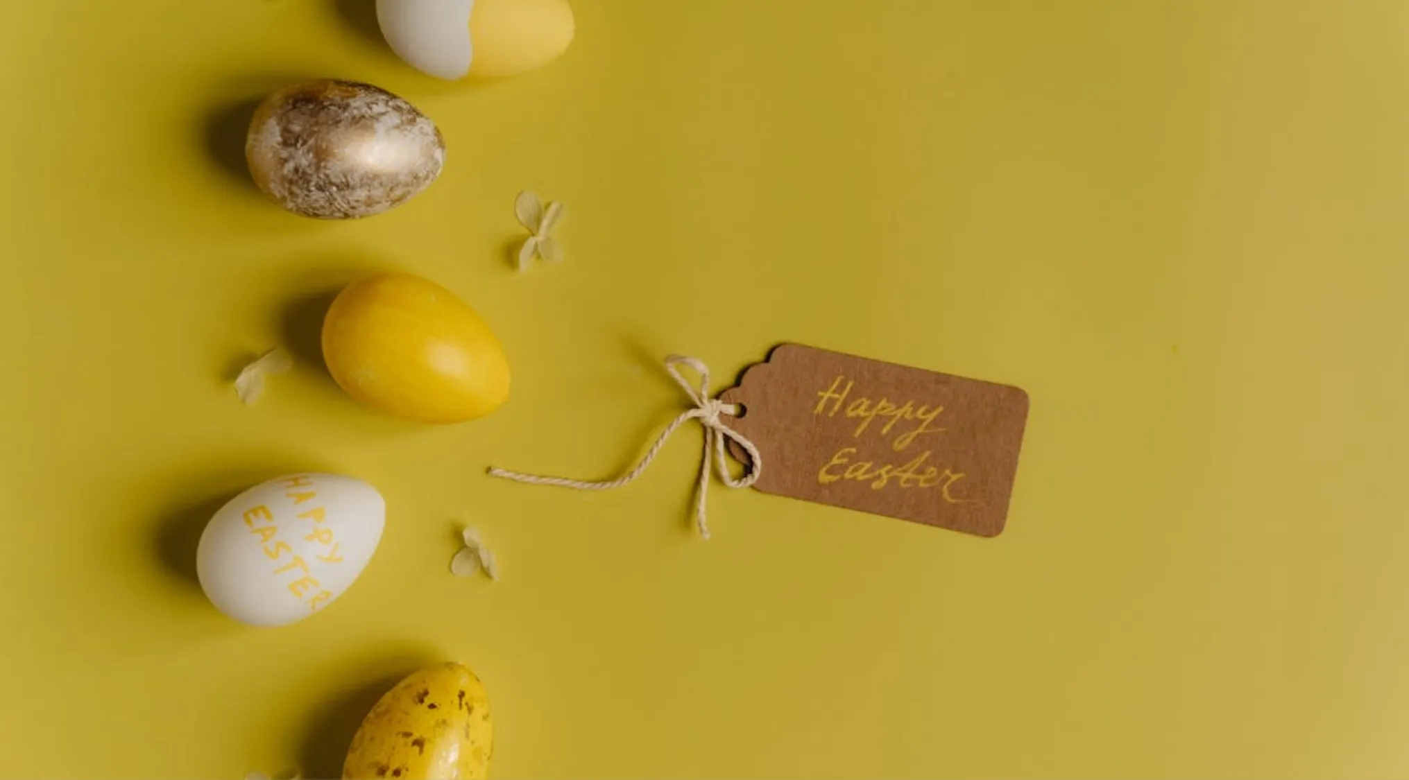 Decorated Easter eggs in yellow and white tones with a Happy Easter tag on a yellow background for UK citizenship test.