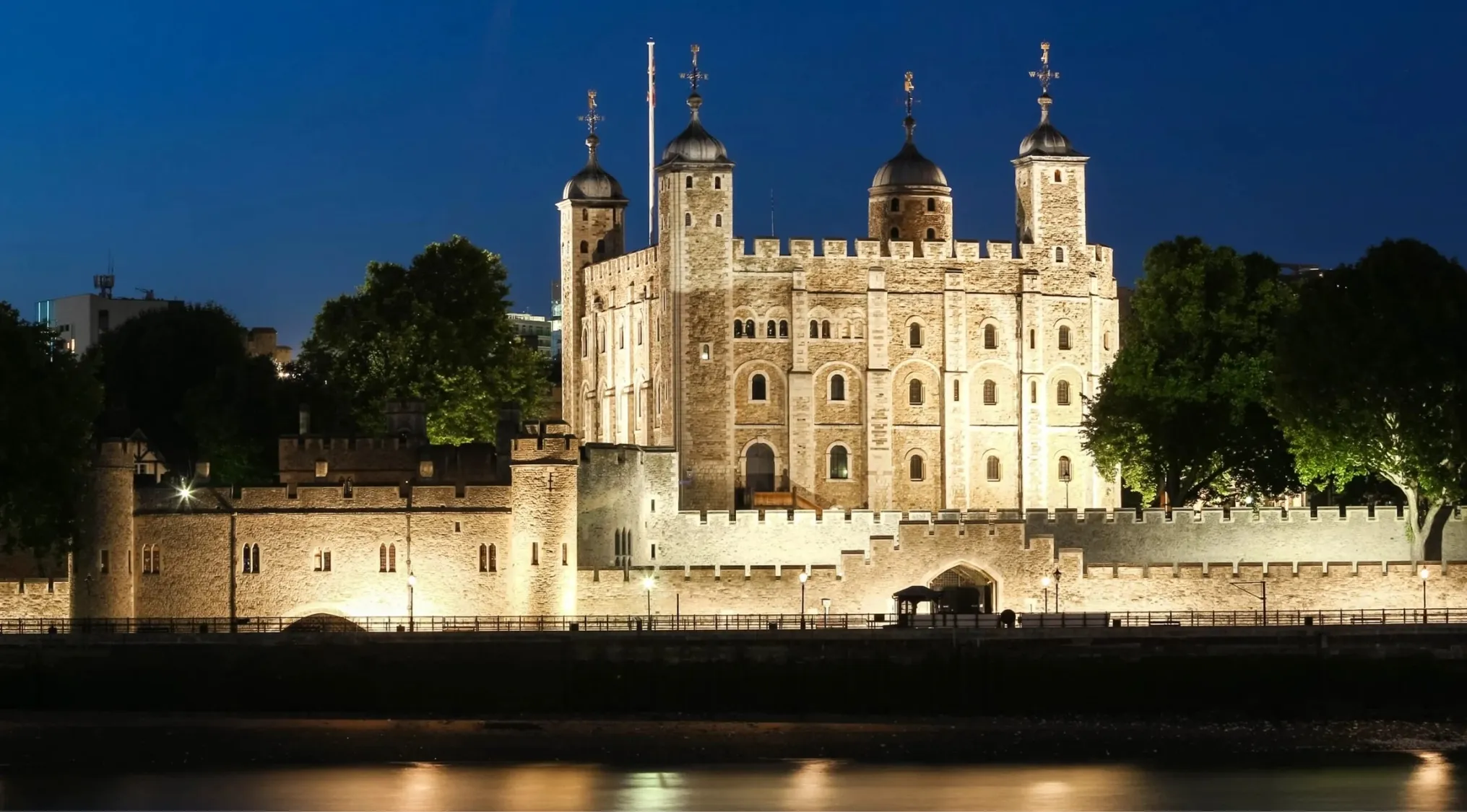 Tower of London illuminated at night with reflections on the river, part of UK citizenship test questions about its builder