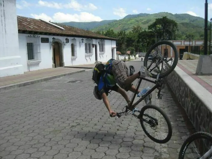 Person mid-fall on a bicycle, creating a surprising and unintended photo moment in a paved street setting.
