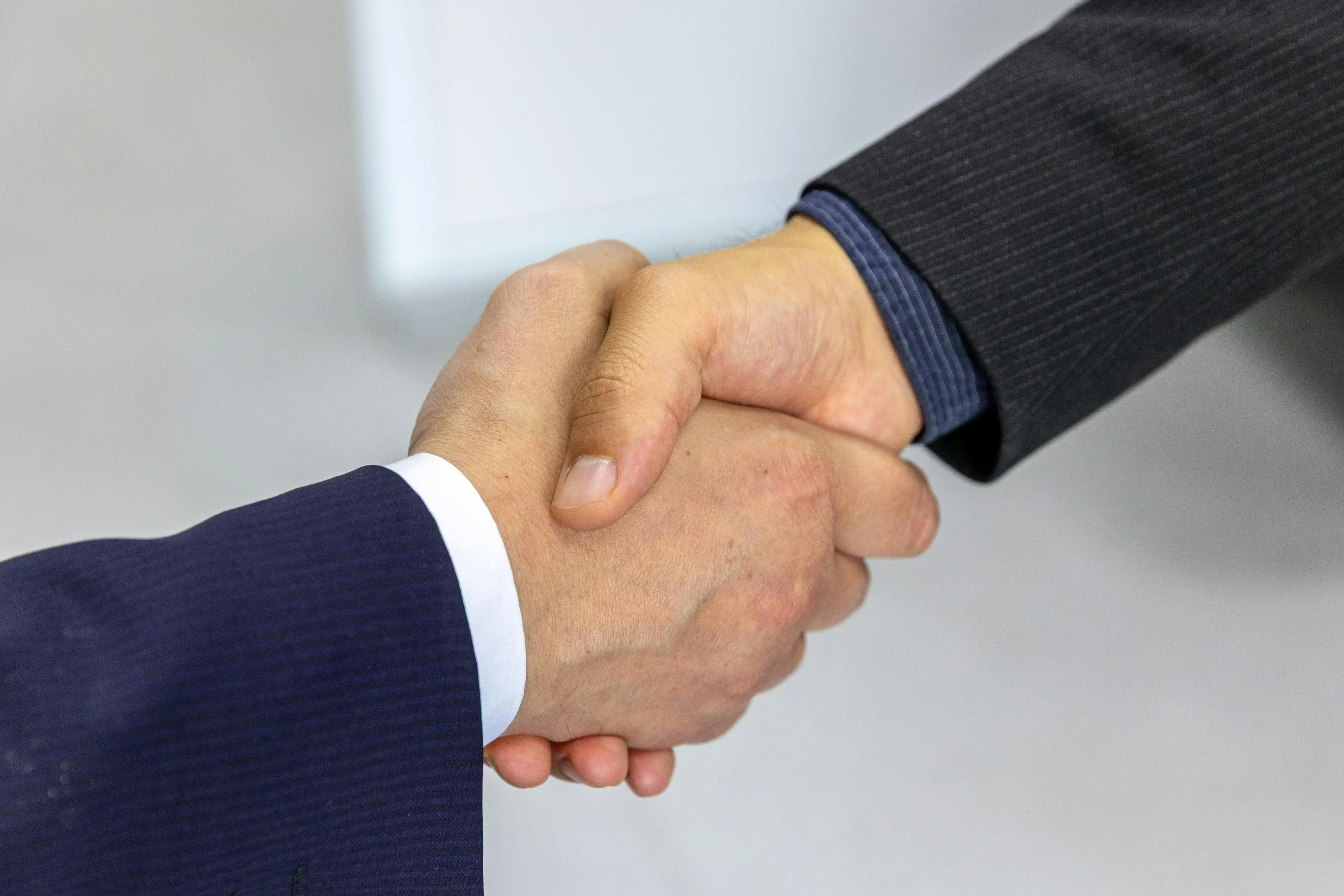 Two people in suits shaking hands representing separation of powers importance in democracy concept.