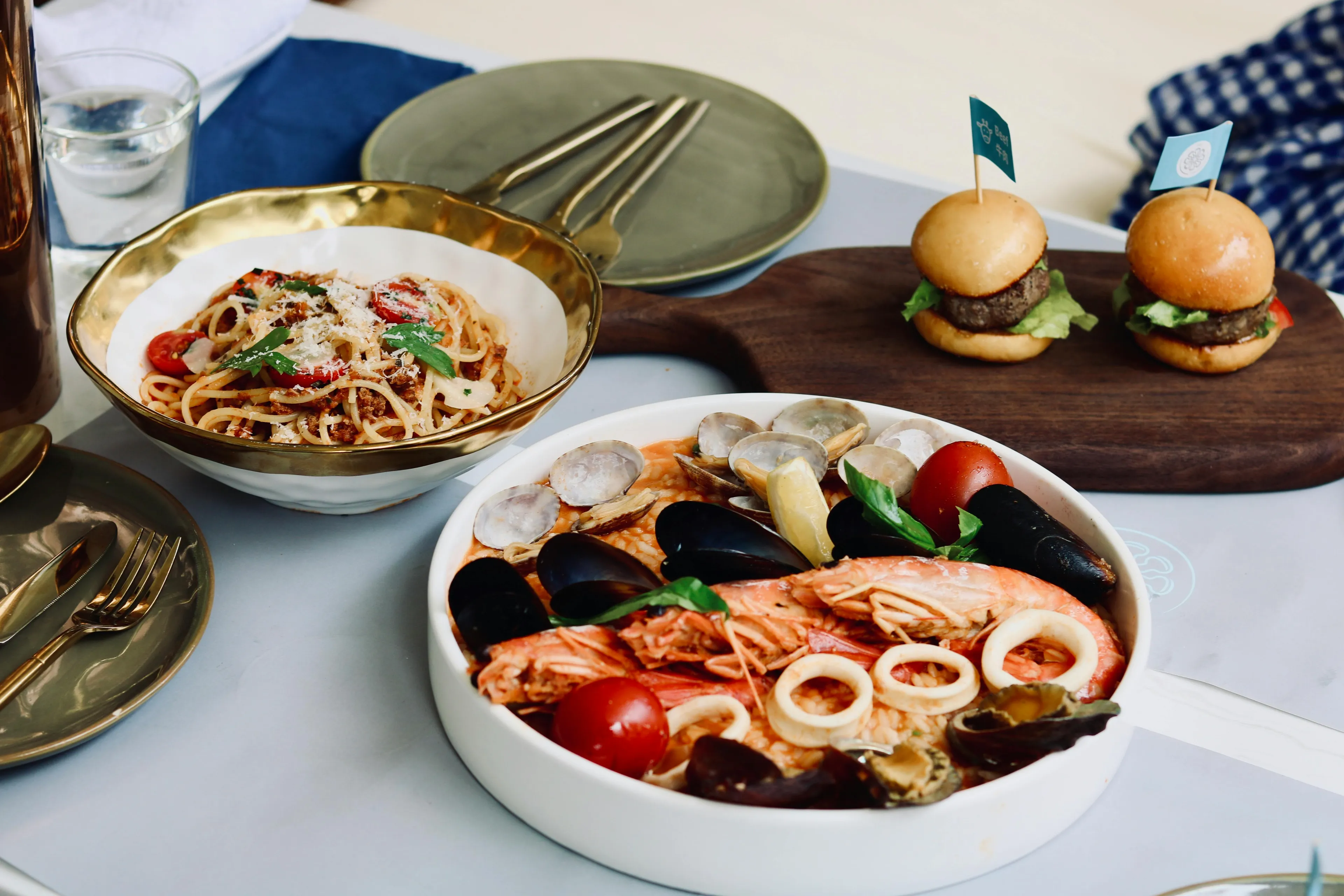 Seafood pasta dish with shrimp, clams, and mini burgers on a table illustrating energy stored in food concept.