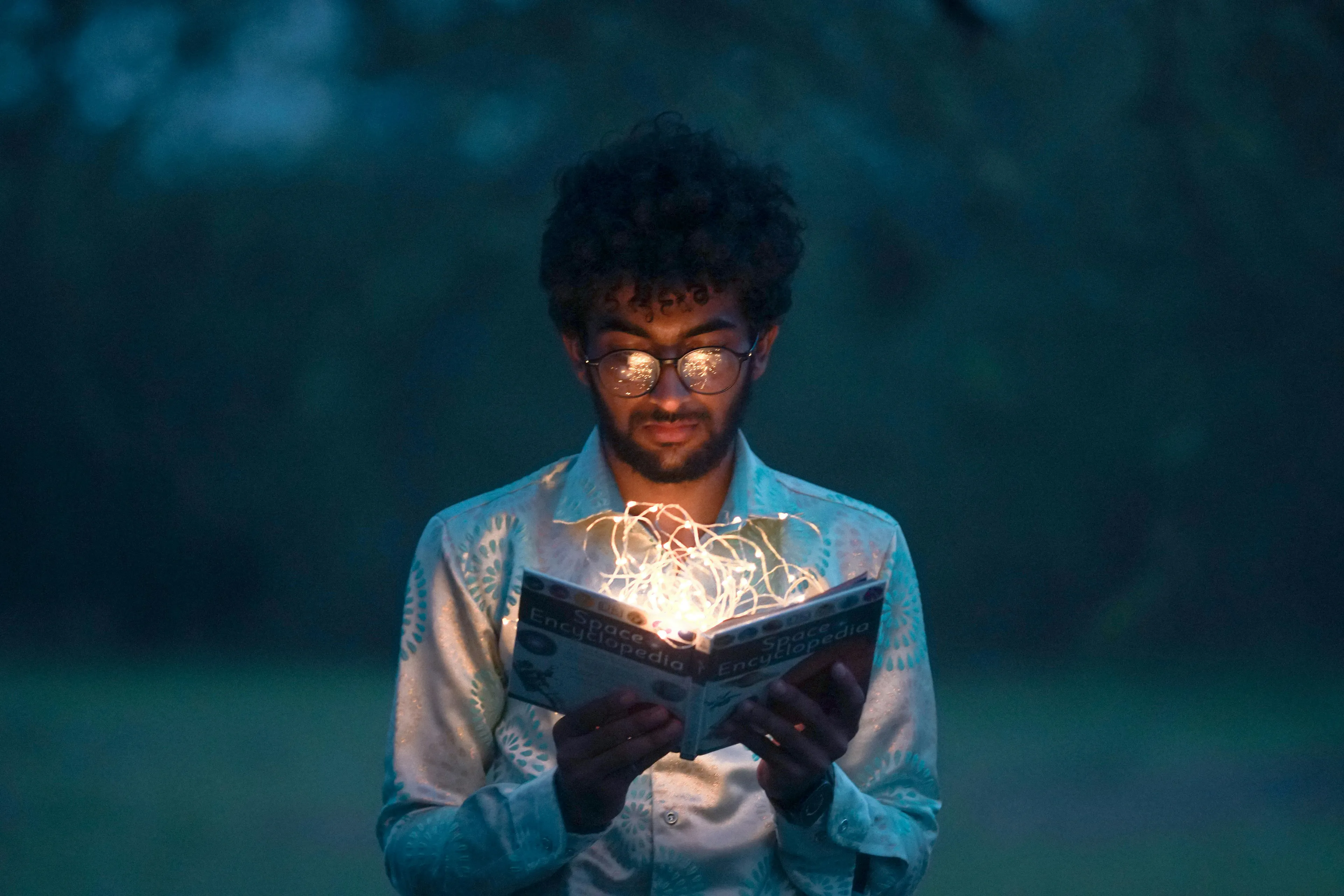 Young man reading a book with lights glowing inside, symbolizing literature and the storytelling climax concept.