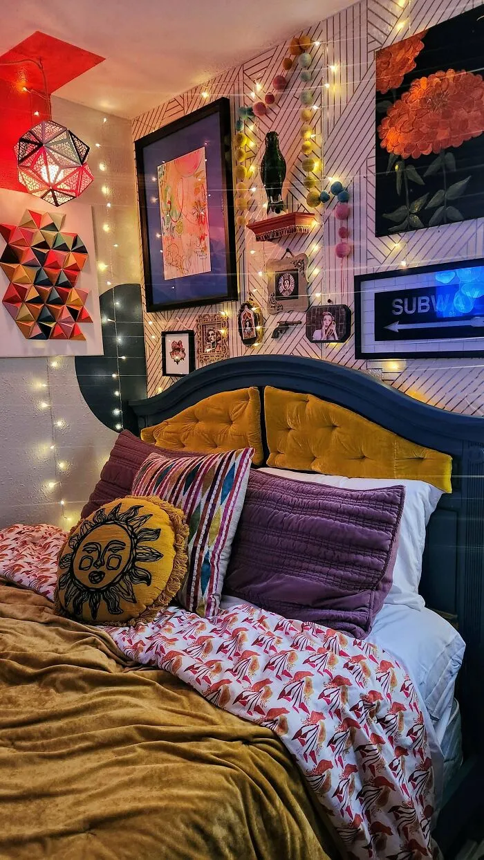 Cozy bedroom decked out with vibrant pillows, patterned bedding, wall art, and string lights embracing more is more home decor.