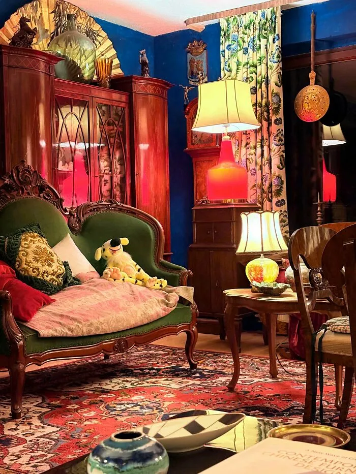 Eclectic living room showcasing more is more home decor with vibrant colors, patterned rug, vintage furniture, and decorative accents.