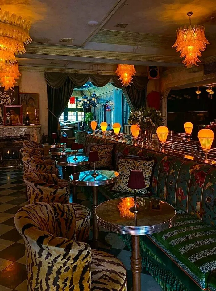 Interior of a home with bold patterned furniture, colorful cushions, and vibrant lighting showcasing more is more decor style.