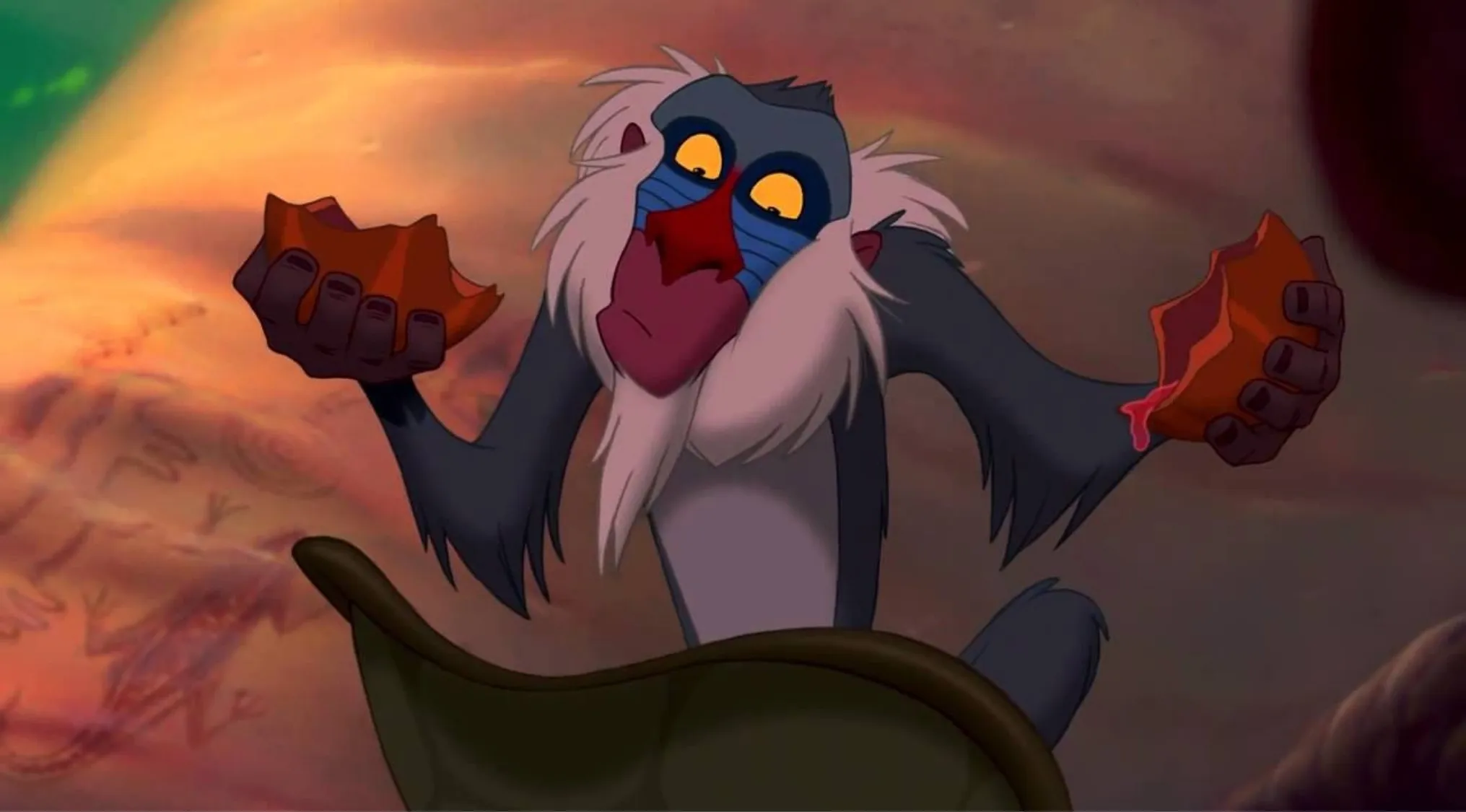 Disney character Rafiki holding a broken fruit in a scene from the animated movie The Lion King.