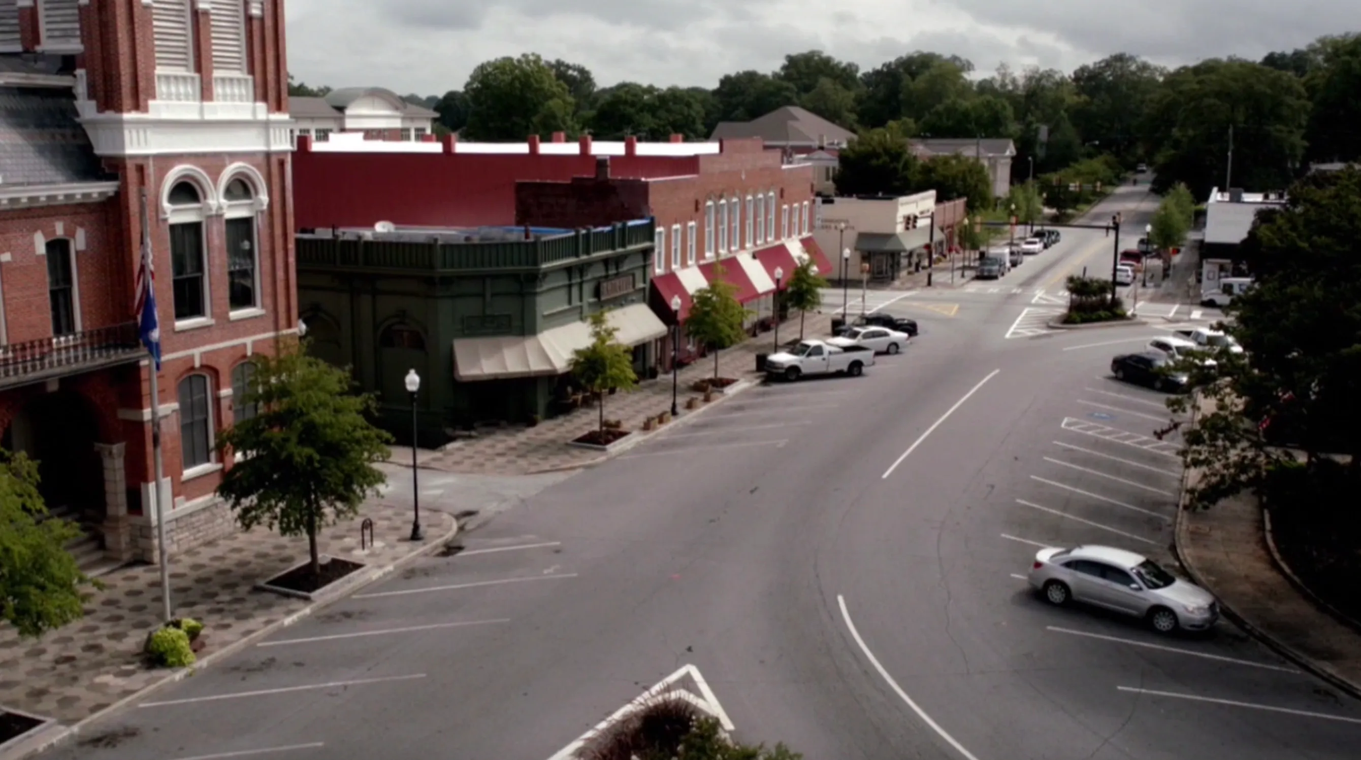 Empty main street of a small town with historic buildings and parked cars, representing fictional locations in TV shows.