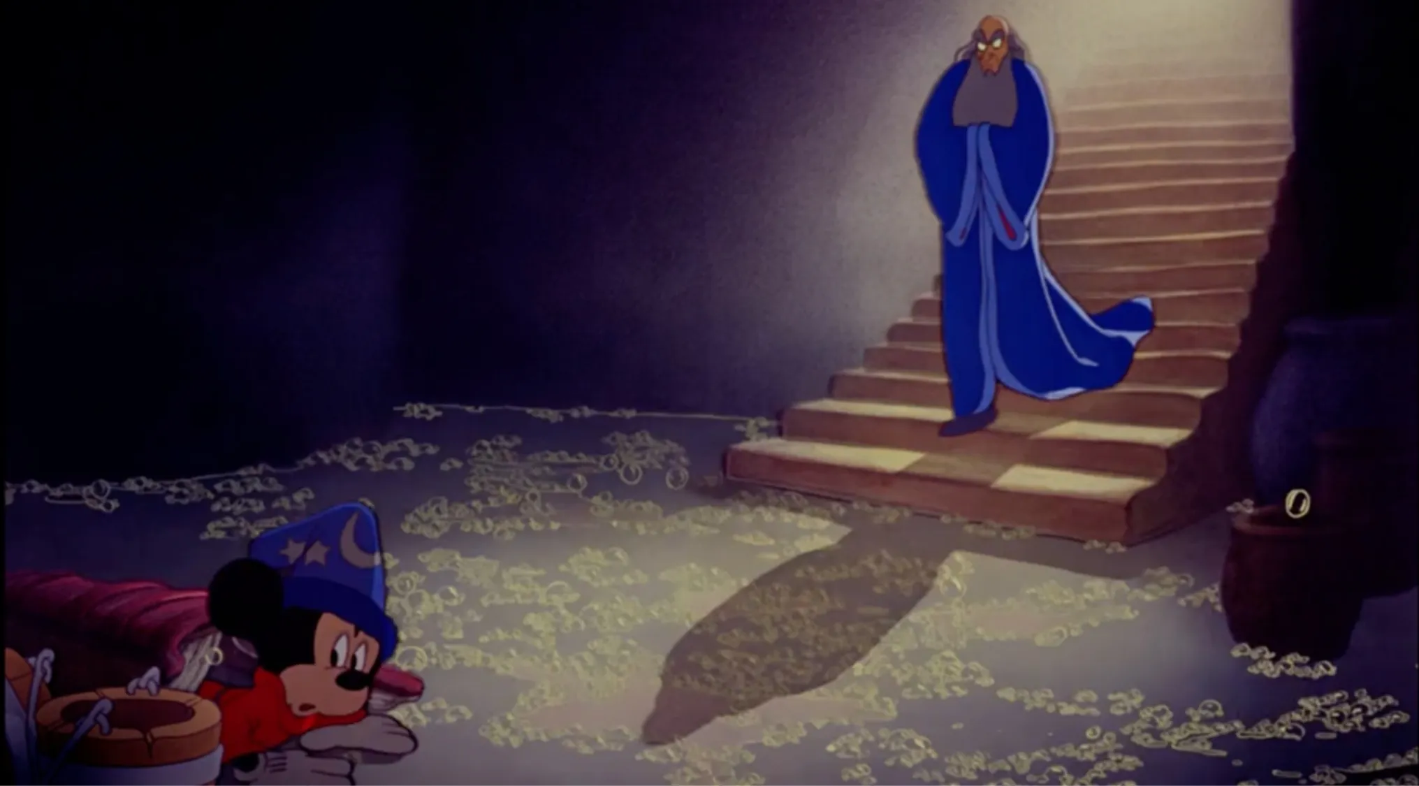 Sorcerer from Disney Fantasia in blue robe descending stairs as Mickey in sorcerer hat watches cautiously on floor.