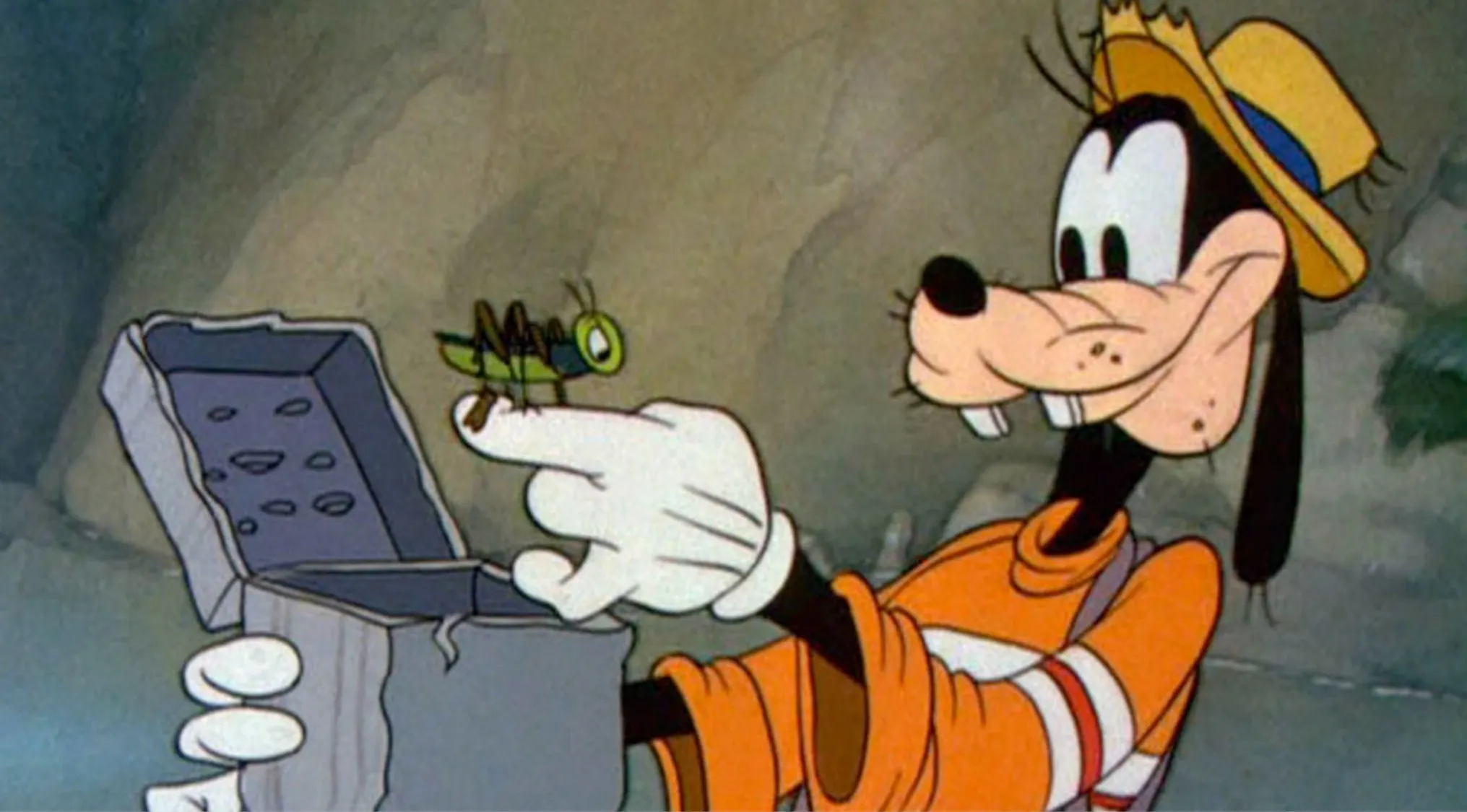 Goofy, a classic Disney character, wearing an orange shirt and yellow hat, holding a gray box and a grasshopper.